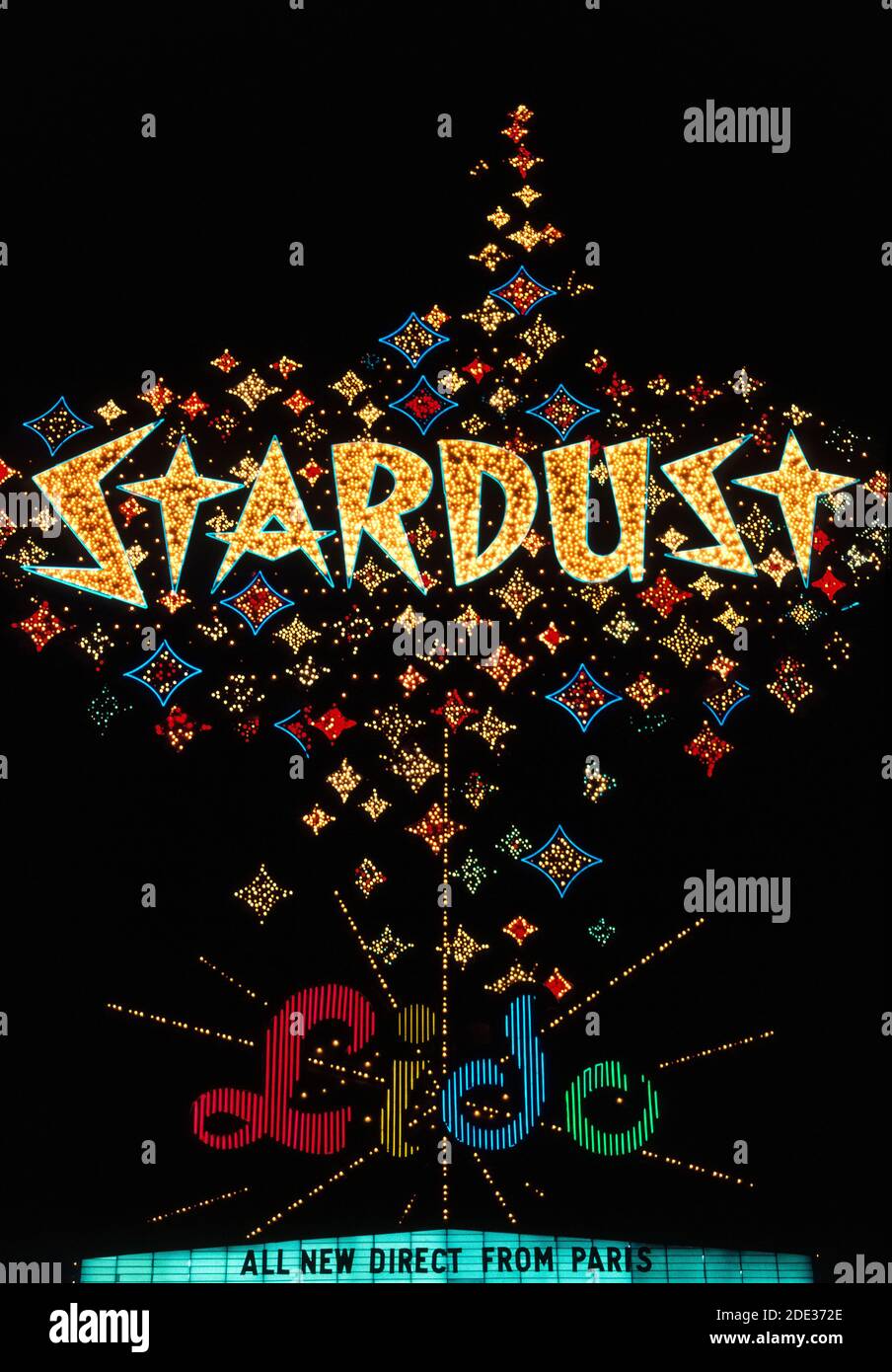 Neon and other colorful lights made this sparkling outdoor sign for the Stardust Resort and Casino stand out at night along Las Vegas Blvd., better known as the Strip, a roadway lined with spectacular resort hotels and casinos just south of the city limits of Las Vegas, Nevada, USA. The Stardust opened in 1958 in that notorious desert destination well-known for its gambling and good times. Its roadside sign changed in design and shape several times before and after this historical photograph was taken in 1983. The Stardust was demolished after closing in 2006, and this sign is only a memory. Stock Photo