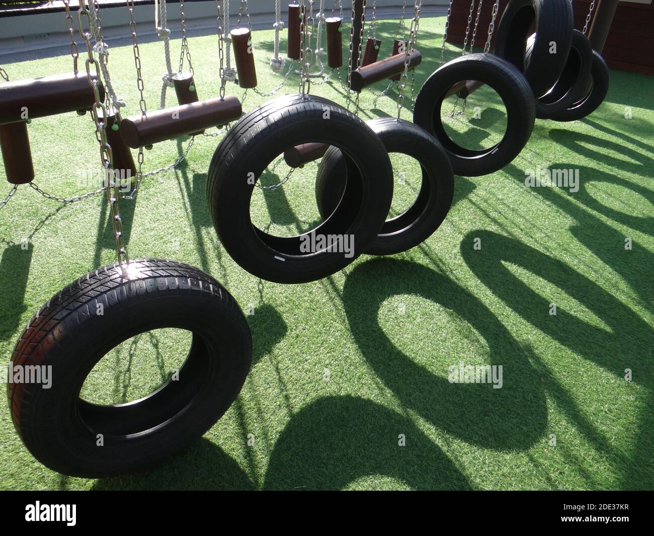 Black wheels hanging from chains on playground Stock Photo