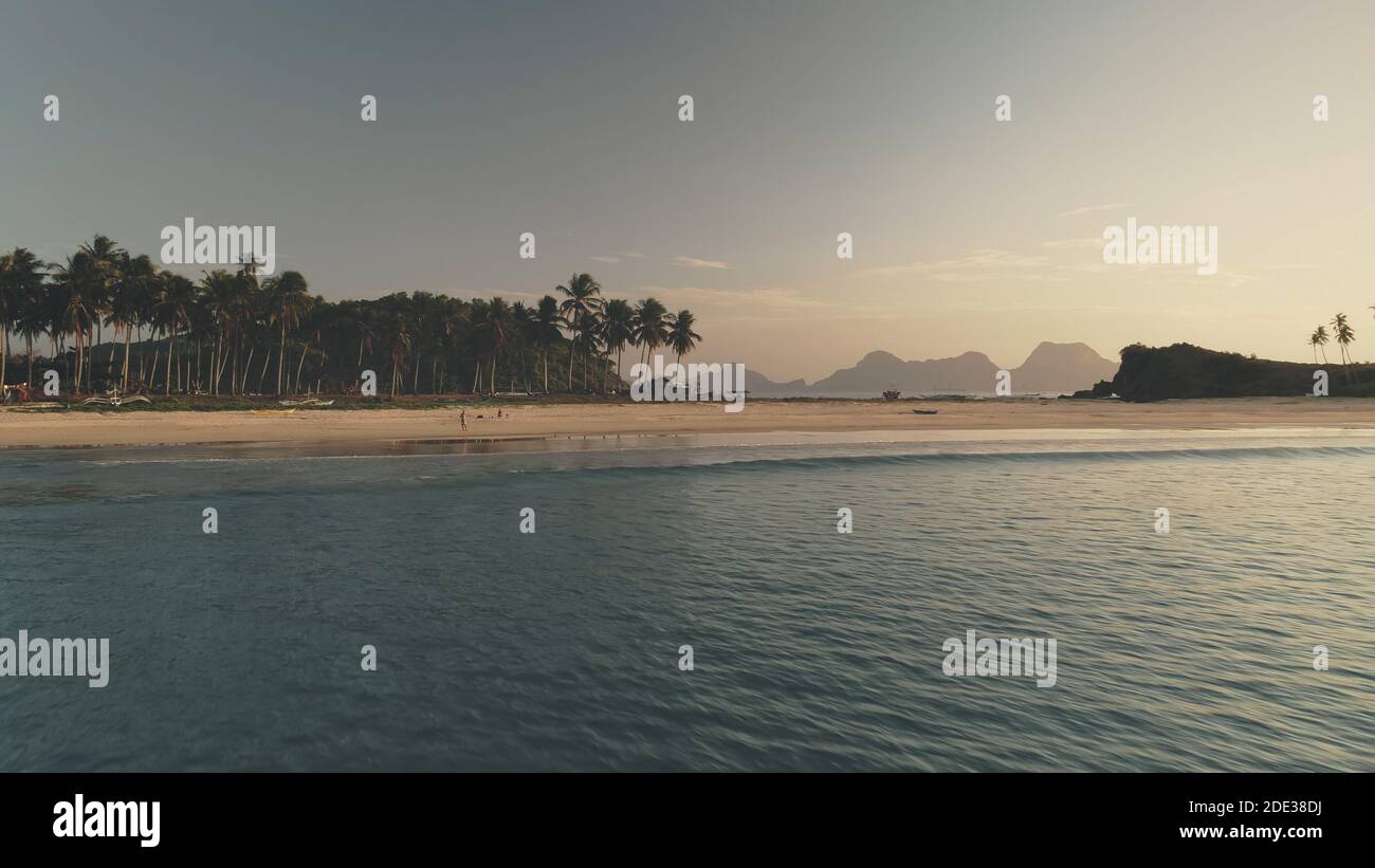 Seascape at sand beach with palm trees at sea shore aerial. Summer tourist vacation at tropic paradise island of El Nido, Philippines, Visayas Archipelago. Cinematic sunlight soft shot Stock Photo