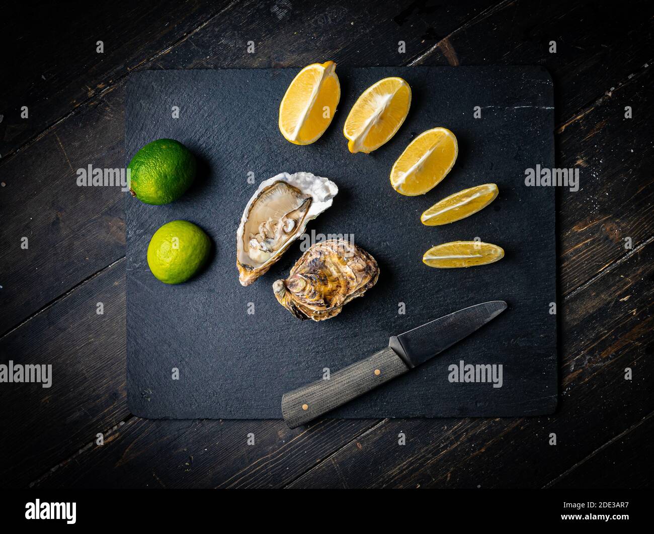 Fresh oysters on a black stone background. Top view. Oyster dinner in