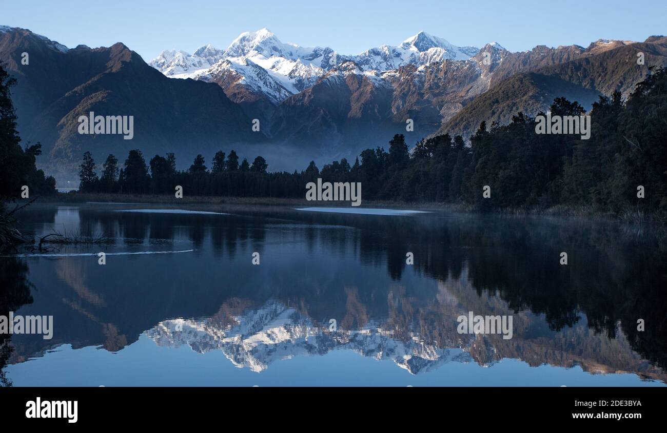Lake Matheson providing stunning reflections of New Zealand's highest peaks - Aoraki (Mount Cook) and Mount Tasman. Stock Photo