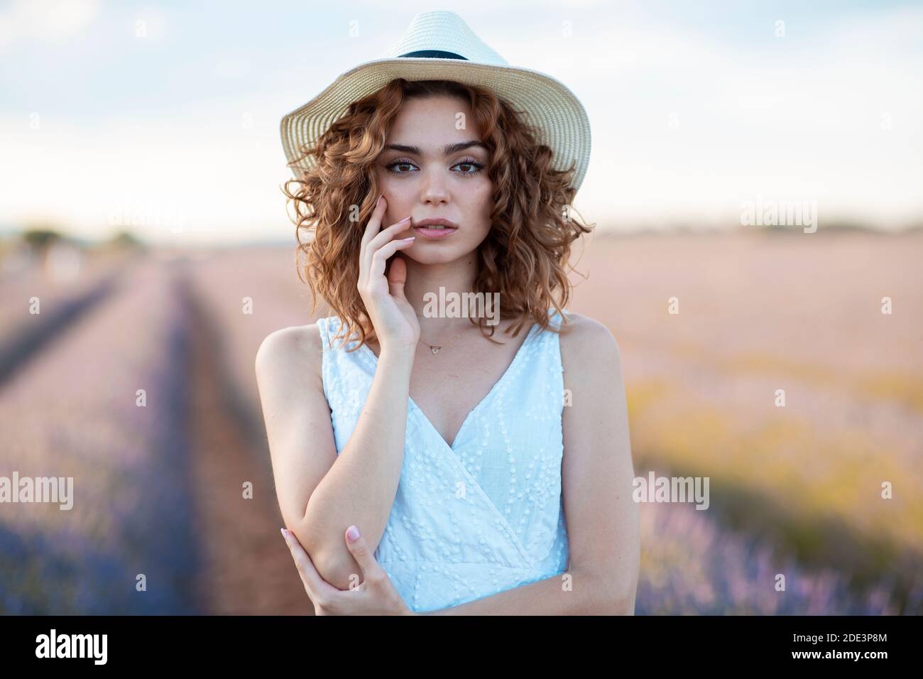woman with curly hair wearing a hat in 