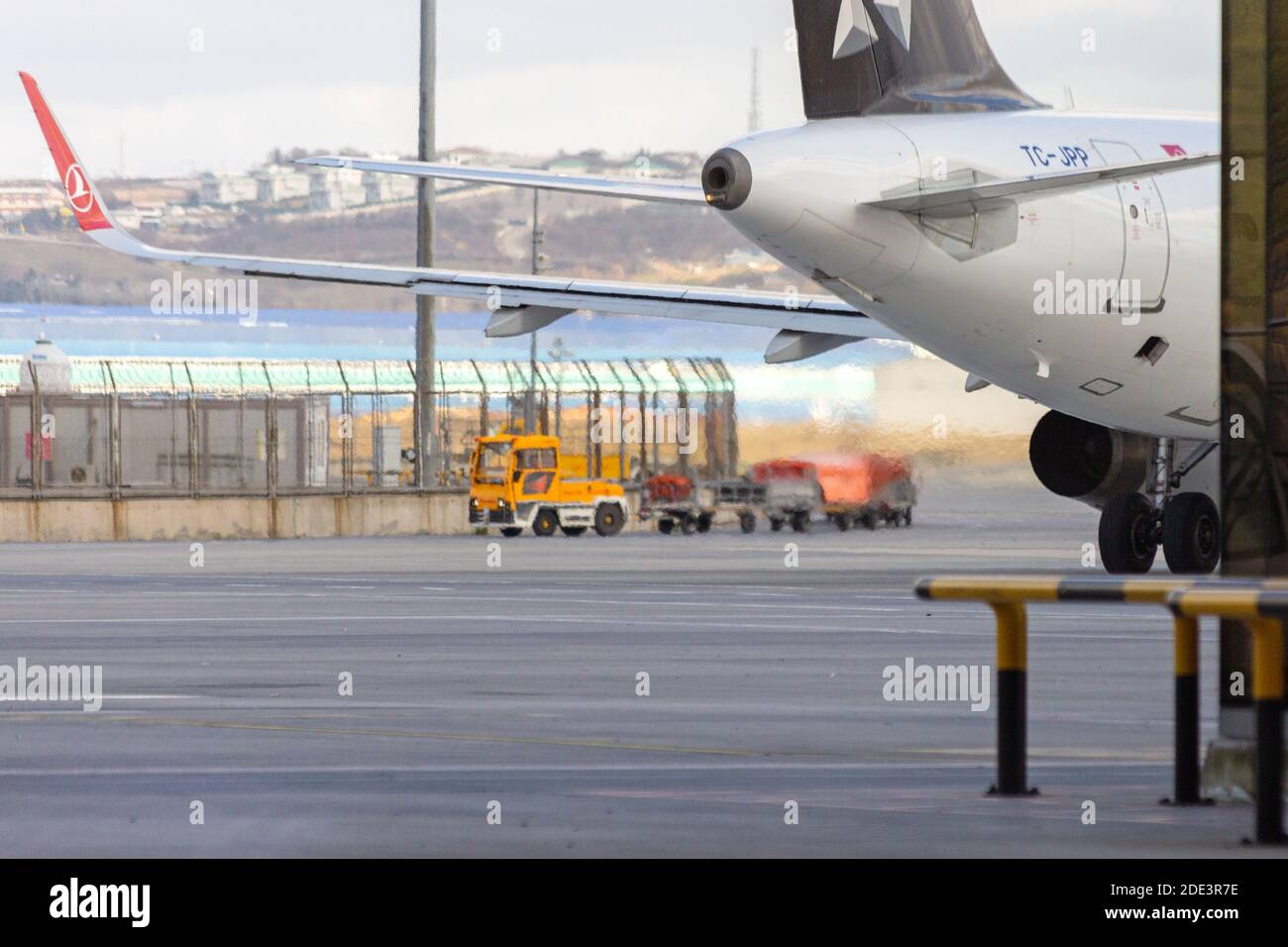 Heat and exhaust dissipation from an airplane engine on the airport tarmac. Luggage carrier truck on the background. Sabiha Gokcen Airport Stock Photo
