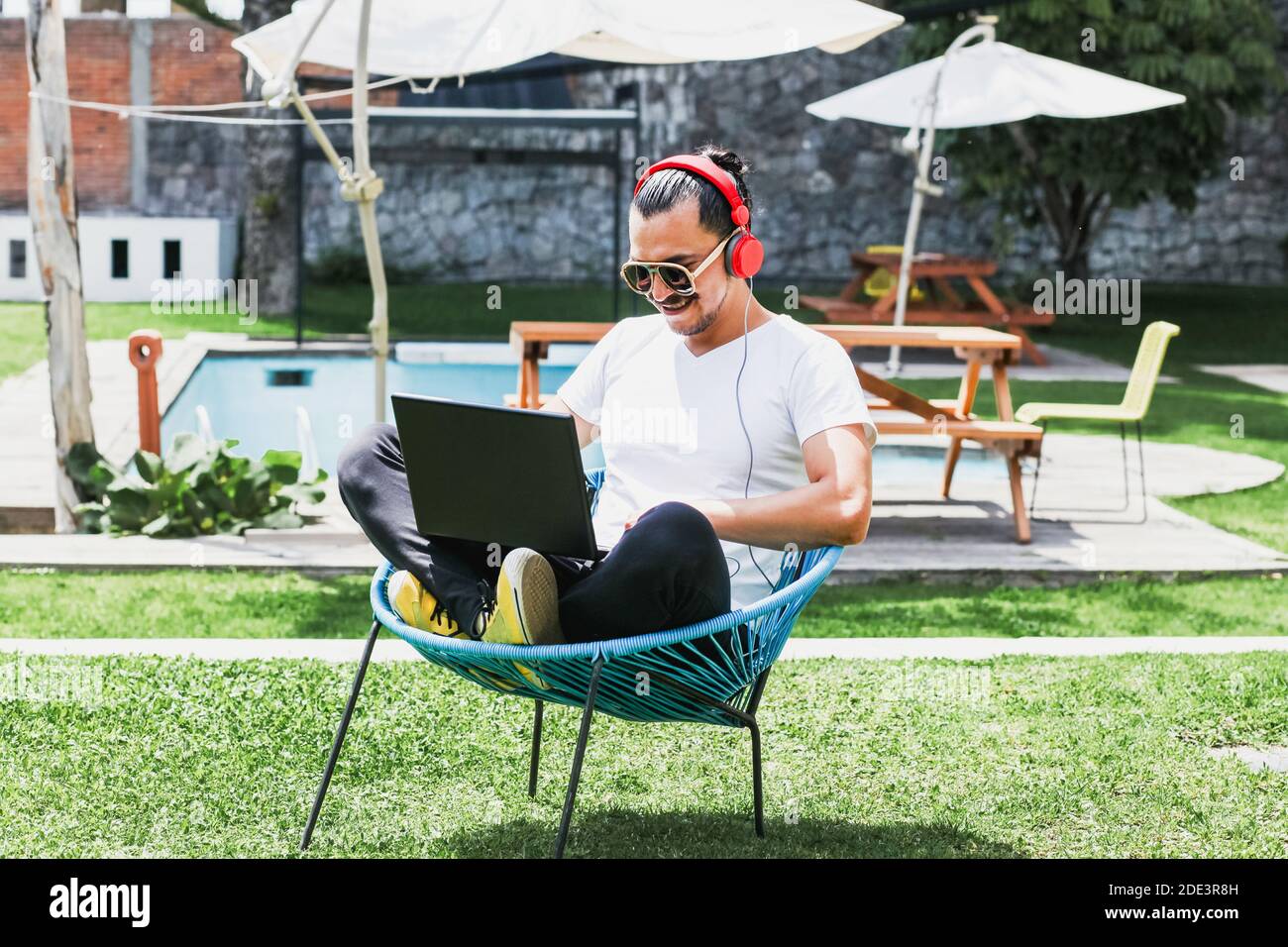 latin man with laptop and headphones at home terrace outdoor in Mexico Stock Photo
