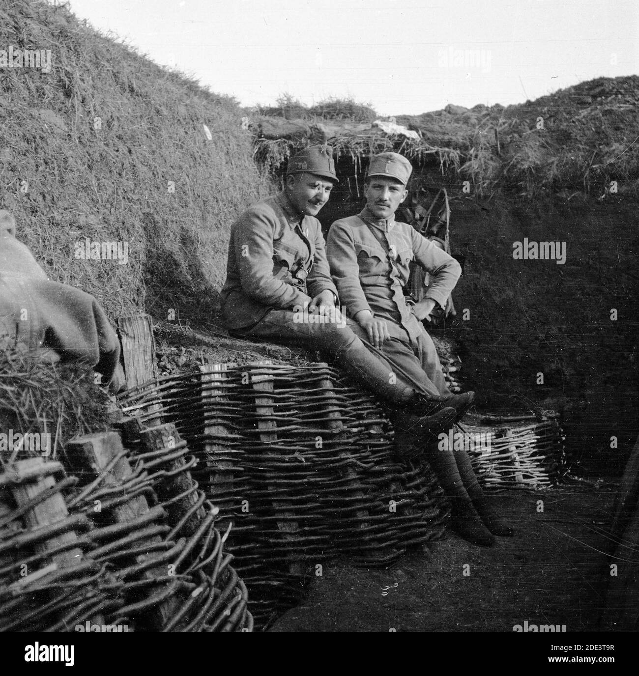 Austro-Hungarian army during the First World War. Two resting soldiers, one of them smiling, in Austrian uniforms sitting in a trench witch sides reinforced by basketwork. Uncertain exact date and location. Stock Photo