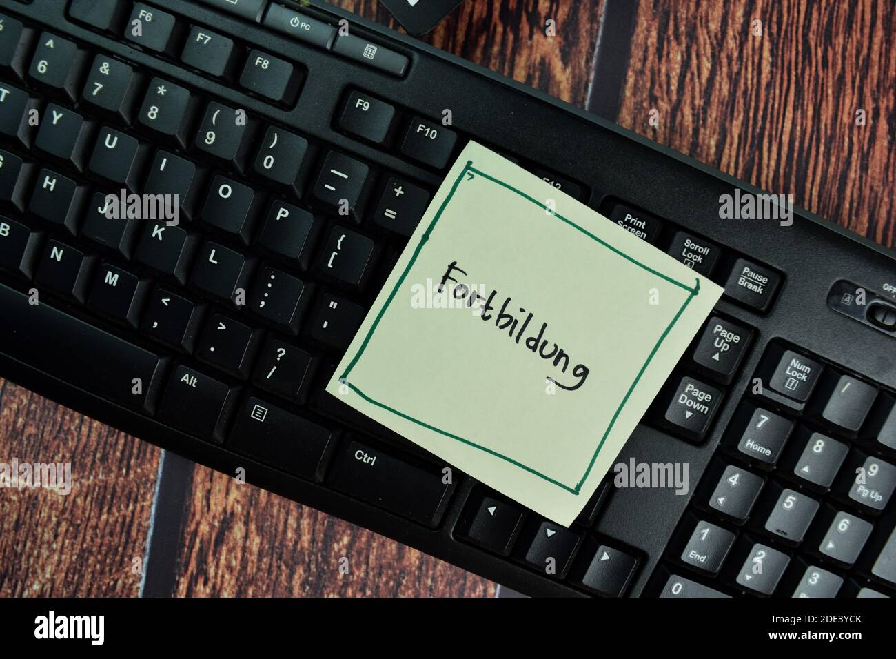 Fortbildung write on a sticky note isolated on office desk. German