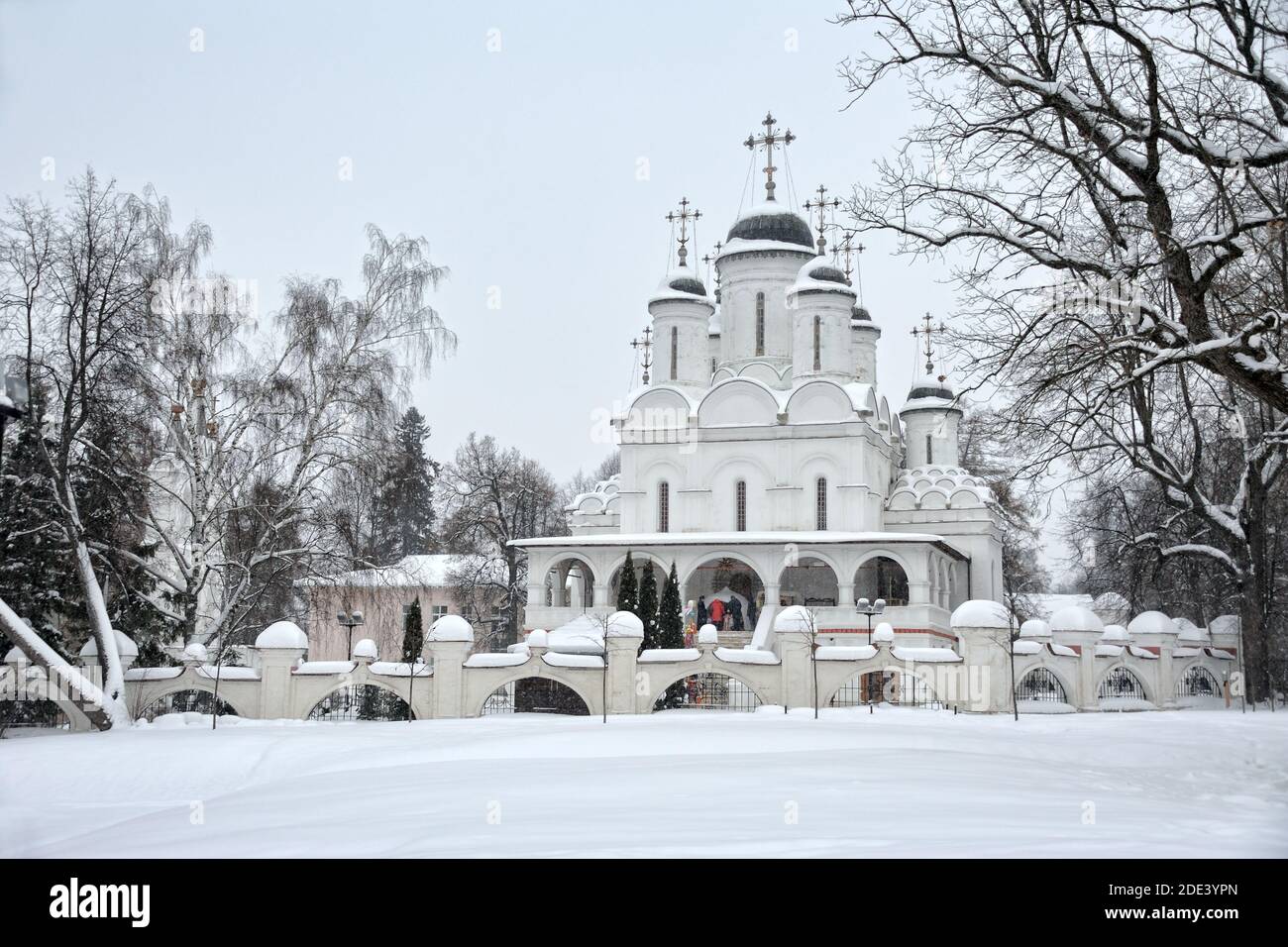 = Transfiguration church in Bolshie Vyazemy in Christmastide =  Old Transfiguration church framed by trees during snowfall in the time of the Orthodox Stock Photo