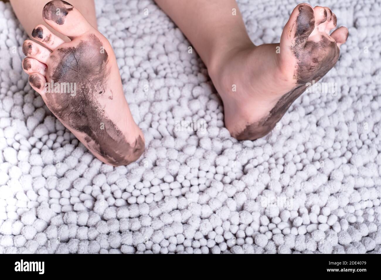 dirty kid feet on a fluffy mat.daily life dirty stain for wash and clean concept Stock Photo