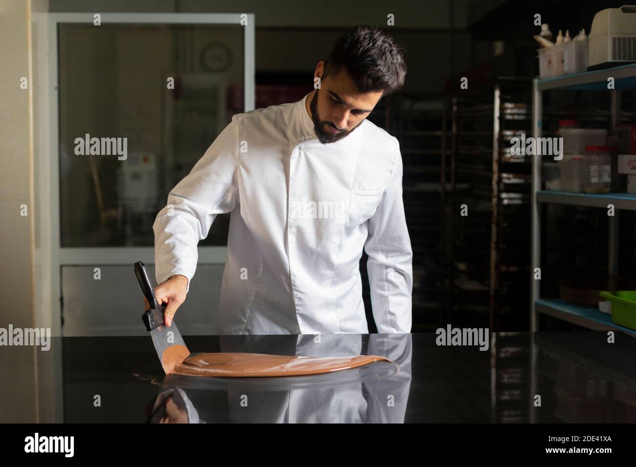 Pastry chef measuring the temperature of the chocolate with an infrared  thermometer, working on the tempering of the chocolate Stock Photo - Alamy