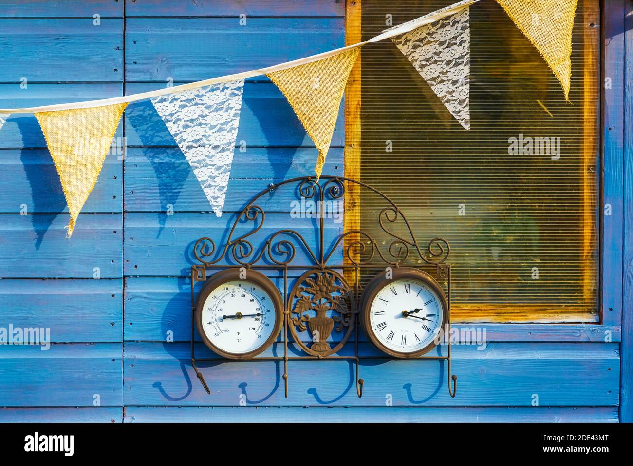 Exterior of a garden shed with bunting and a clock and weather thermometer, Garden, Kilwinning, Ayrshire, Scotland, UK Stock Photo