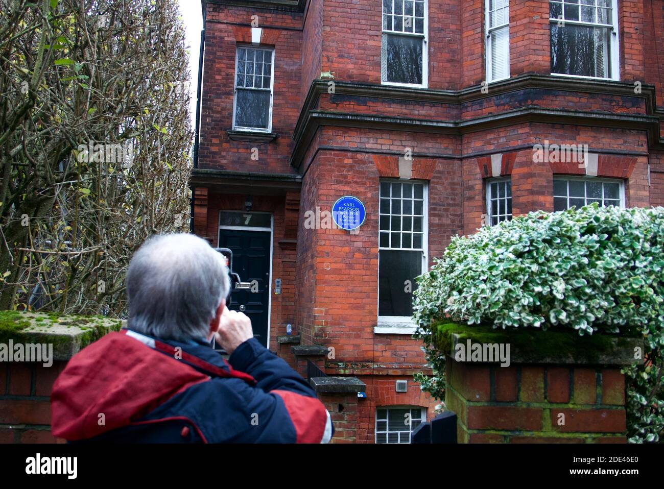 Man taking photo with smartphone of Karl Pearson English Heritage blue plaque in Hampstead Village, London. Stock Photo