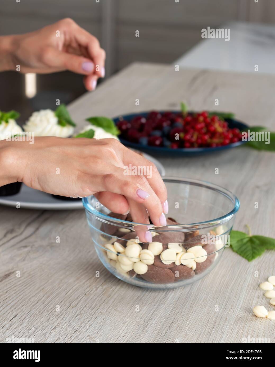 Woman confectioner  decorates  cupcakes with fresh berries , candies and chocolate Stock Photo