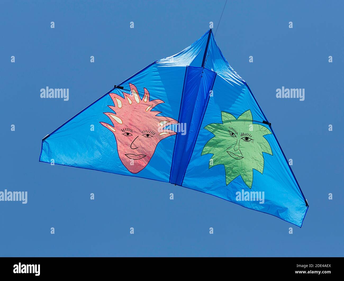 Blue kite with two imaginative faces flying in the blue sky, North Rhine-Westphalia, Germany Stock Photo