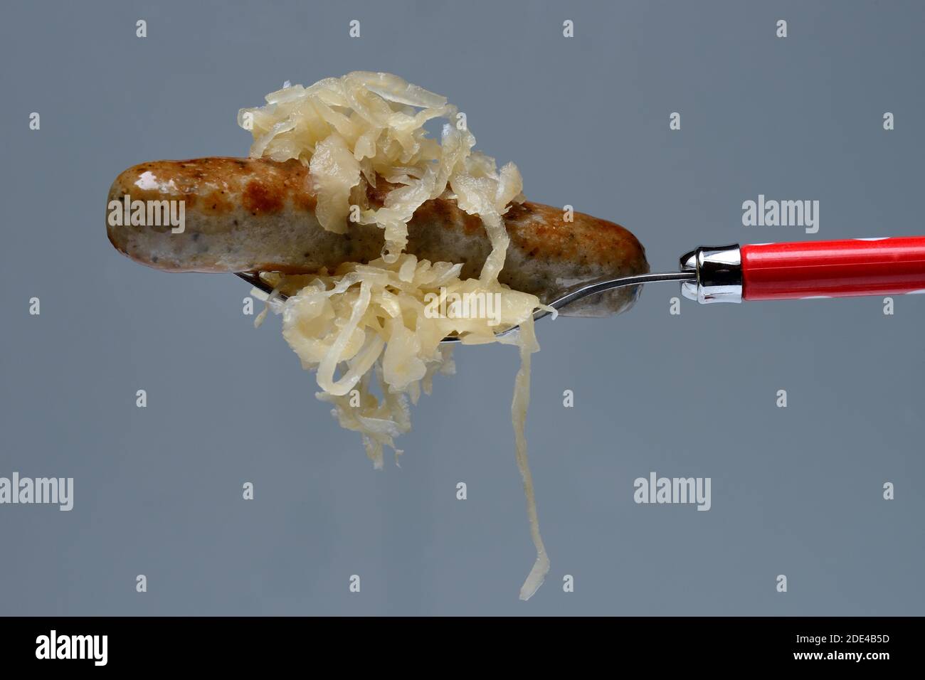 Nuremberg grilled sausages with sauerkraut on fork, Germany Stock Photo