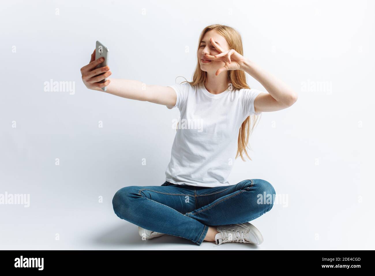The girl in the Studio doing a selfie, white background Stock Photo