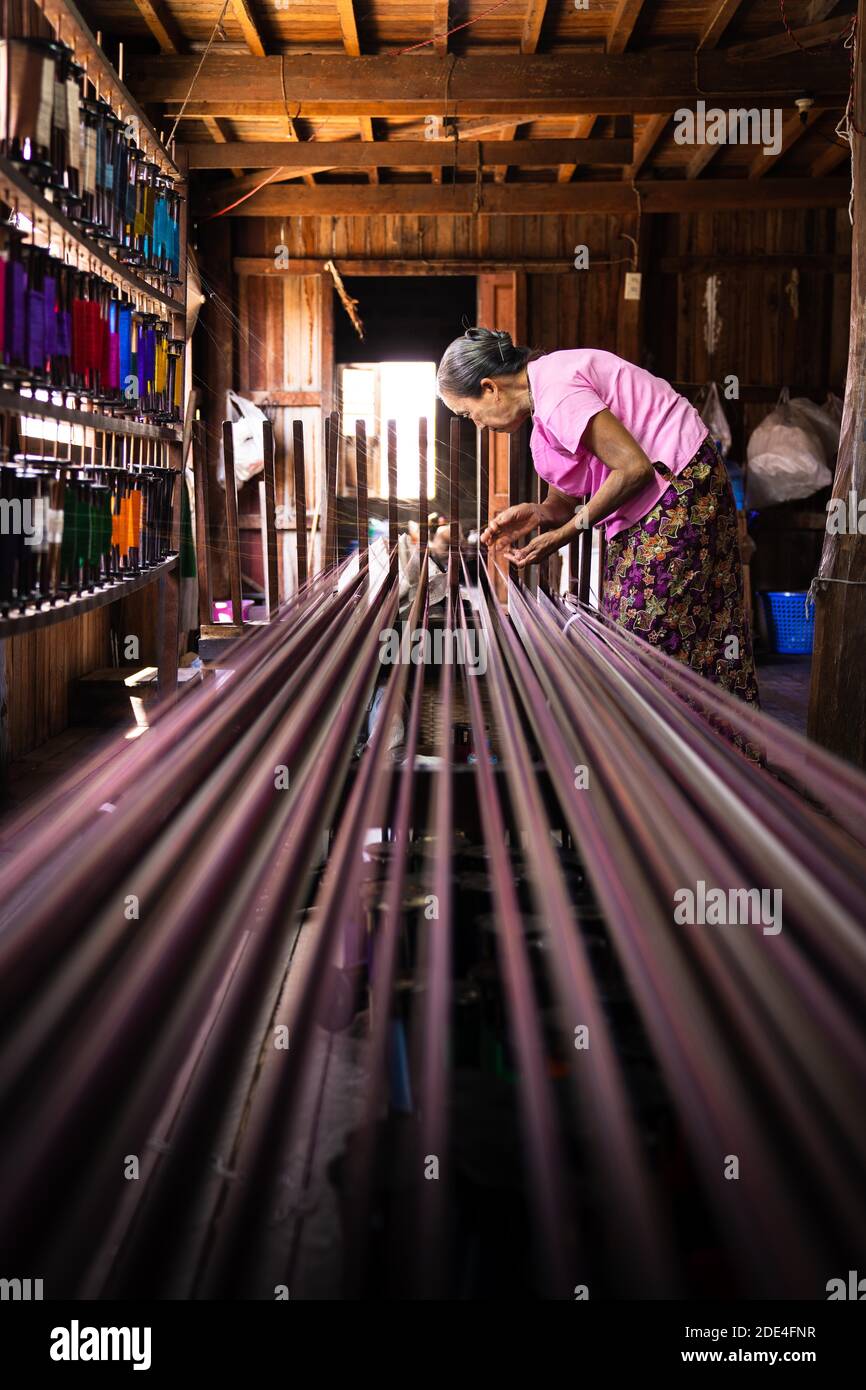 Woman pulling up colourful threads on loom, Lake Inle, Myanmar Stock Photo