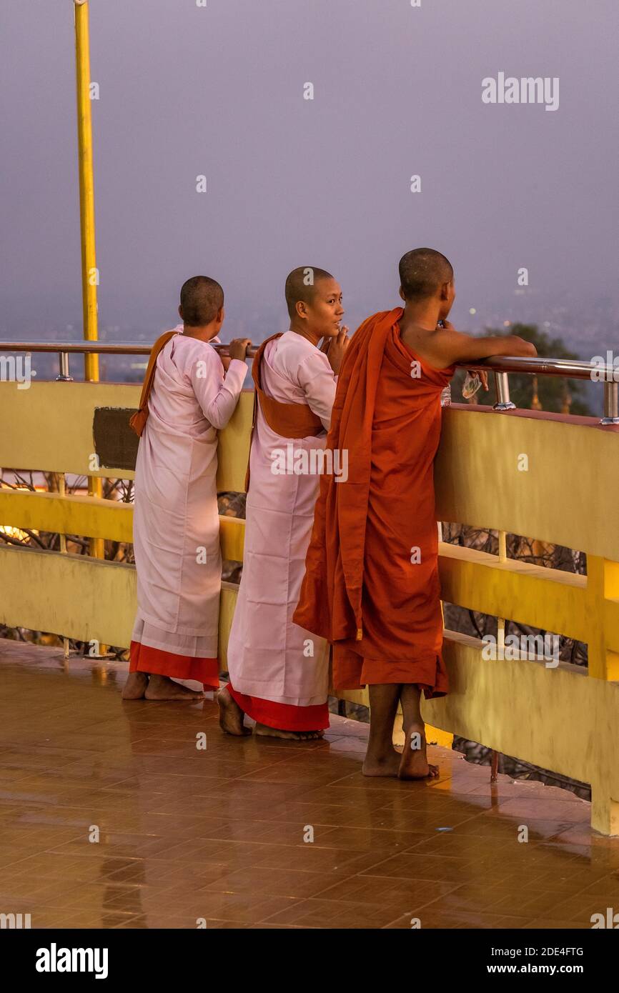 Three female Buddhist nuns at the railing of the Su Taung Pyae Pagoda ...