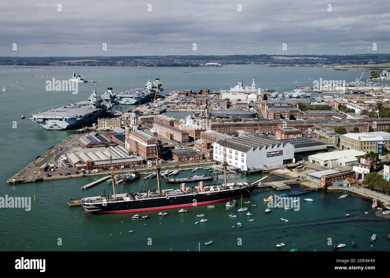 Aerial view of the Royal Navy dockyard in Portsmouth, Hampshire on a sunny summer day.  Aerial view including HMS Warrior, and the aircraft carriers H Stock Photo