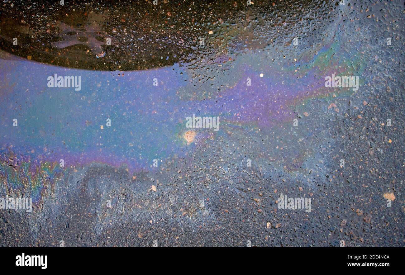 Colorful gas stain on wet asphalt. Oil stain caused by a leak under a