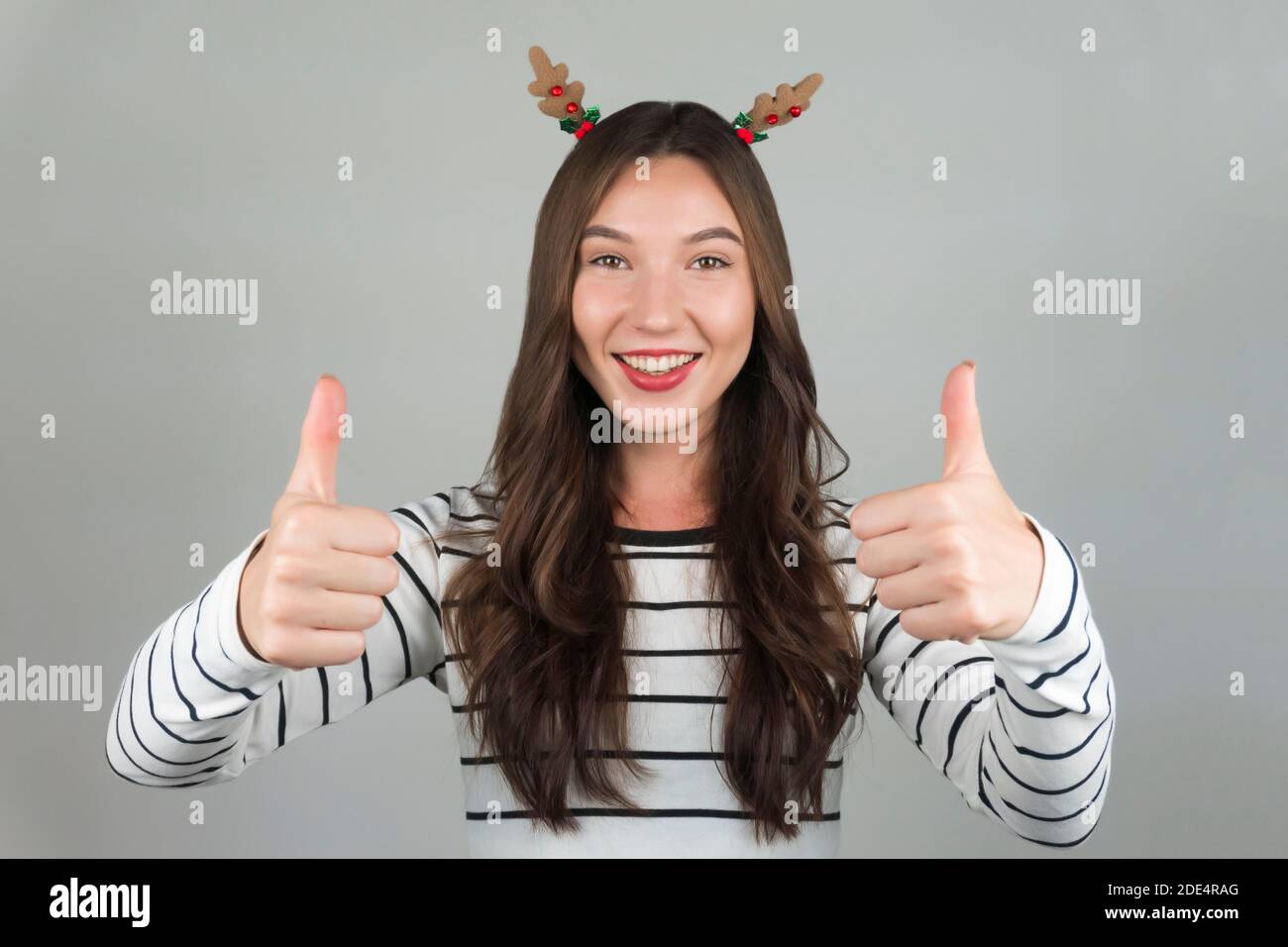 Happy woman with thumbs up. Christmas decorations in hair. High quality photo Stock Photo