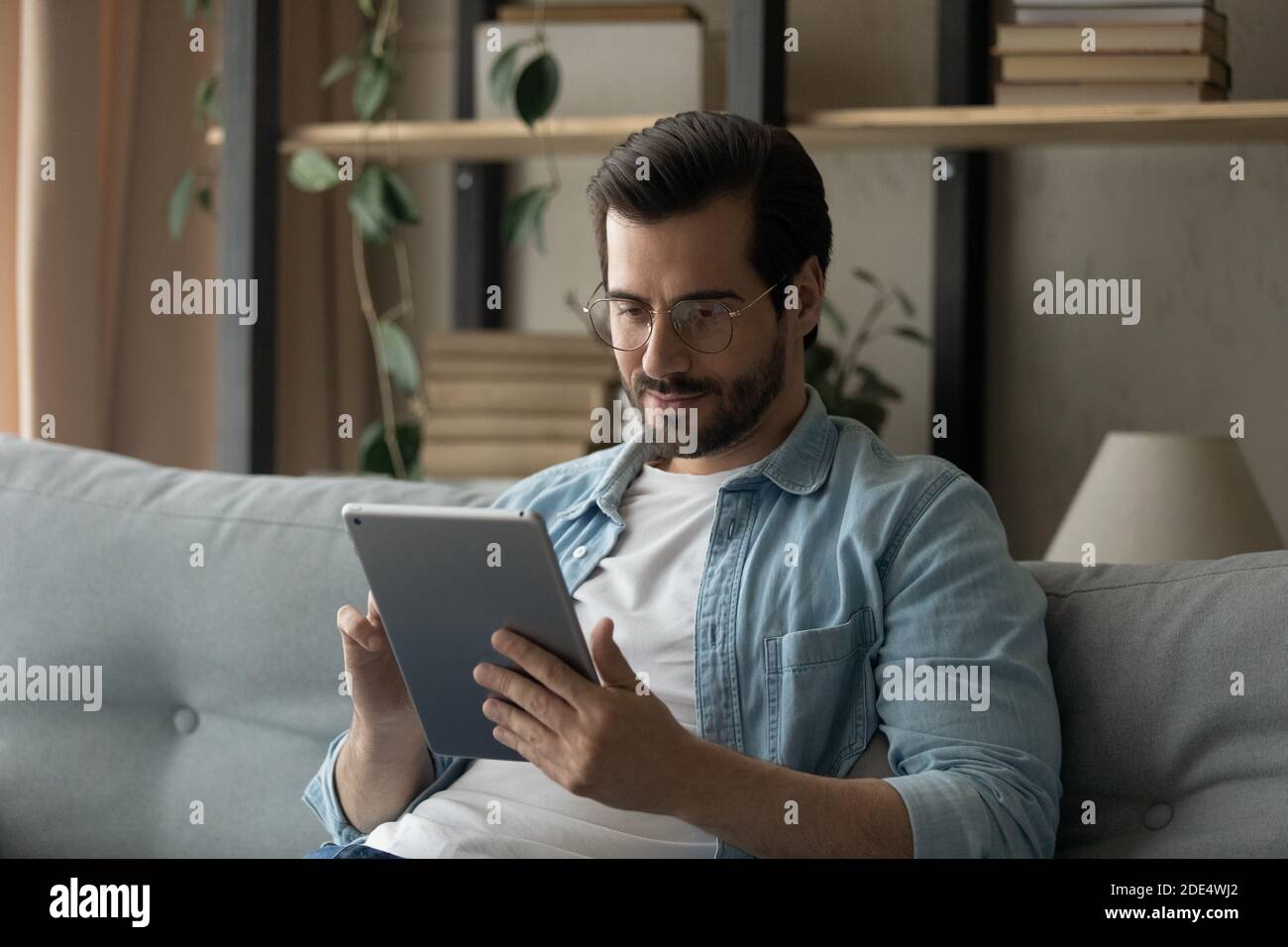 Caucasian man sit on couch using tablet gadget Stock Photo