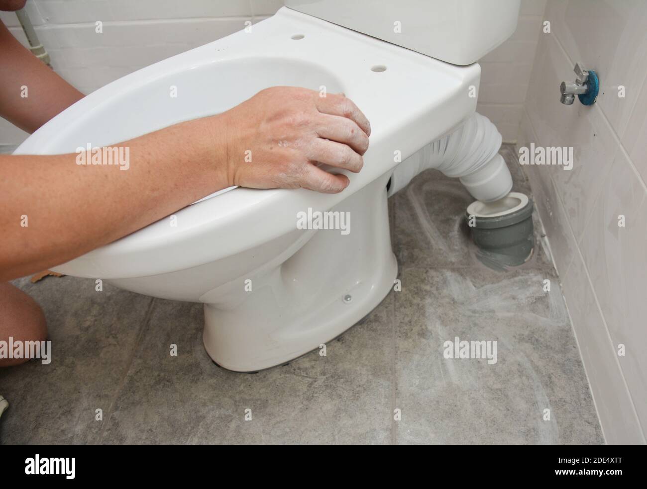 Repairman installing flush toilet, toilet bowl in the bathroom. Stock Photo