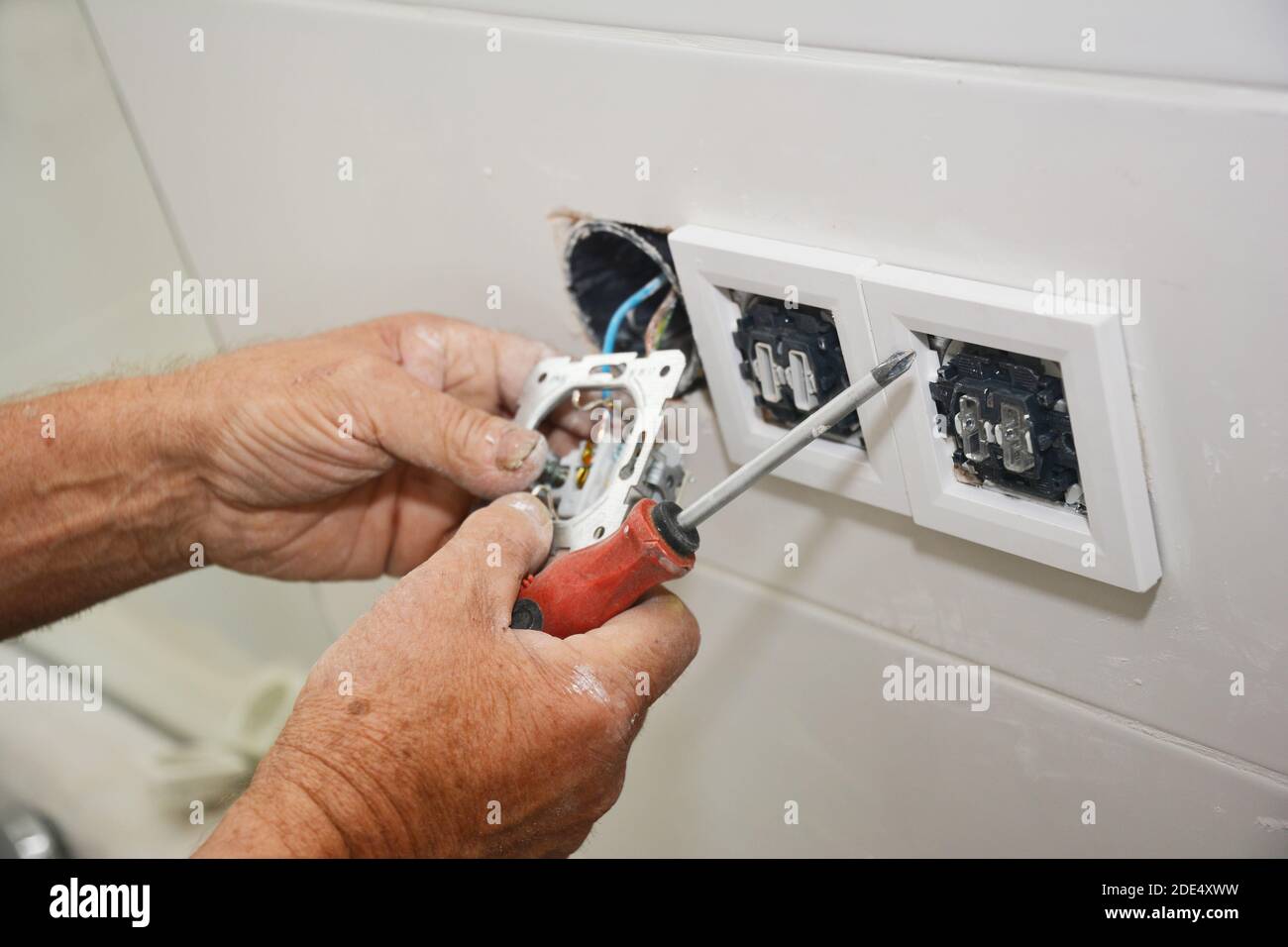 An electrican is repairing and installing a socket, outlet plug. Stock Photo
