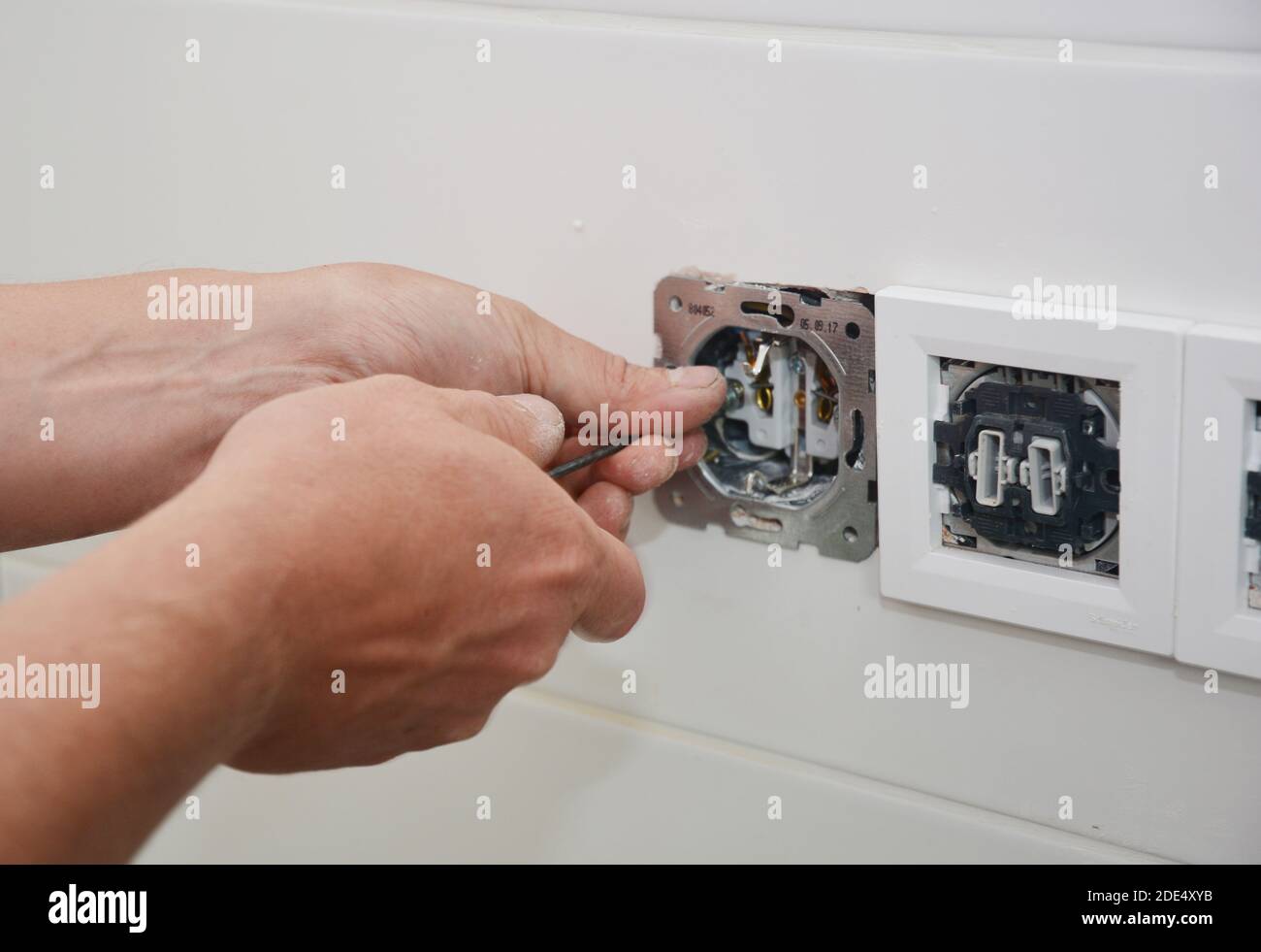 An electrican is repairing and installing a socket, outlet plug and switch. Stock Photo