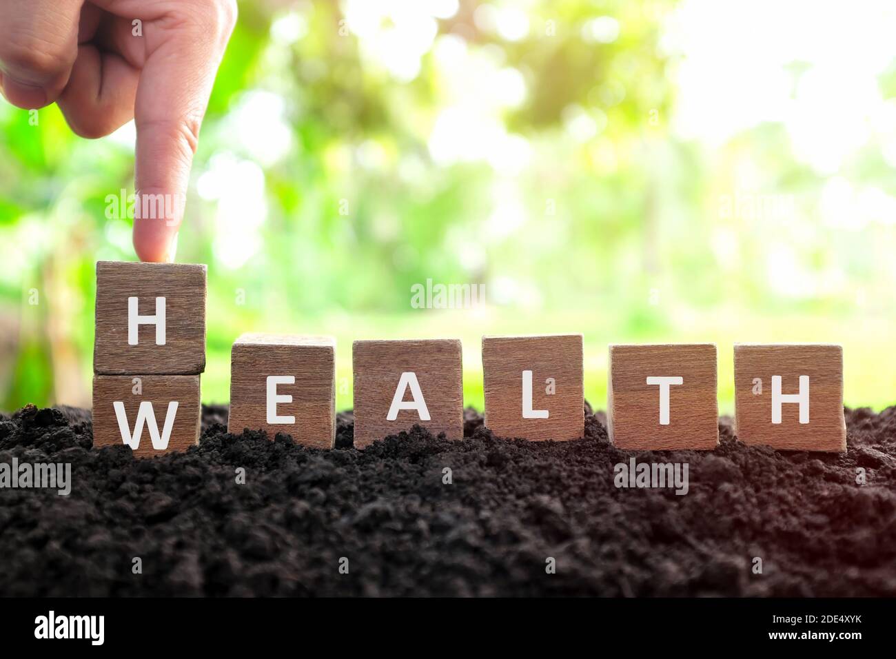Health is wealth concept. Hand changing or flipping wooden blocks dice with word wealth to health in natural background. Stock Photo