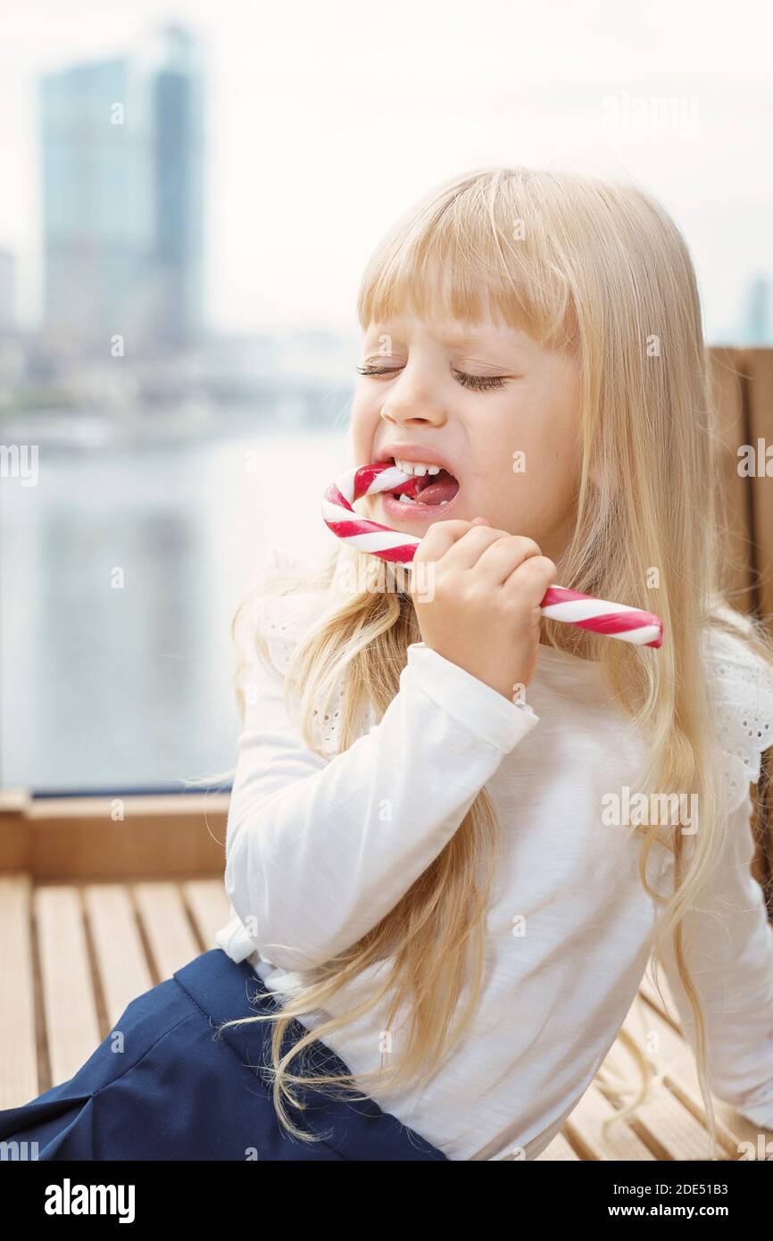 beautiful little girl takes a bite of caramel and has pain. tooth decay