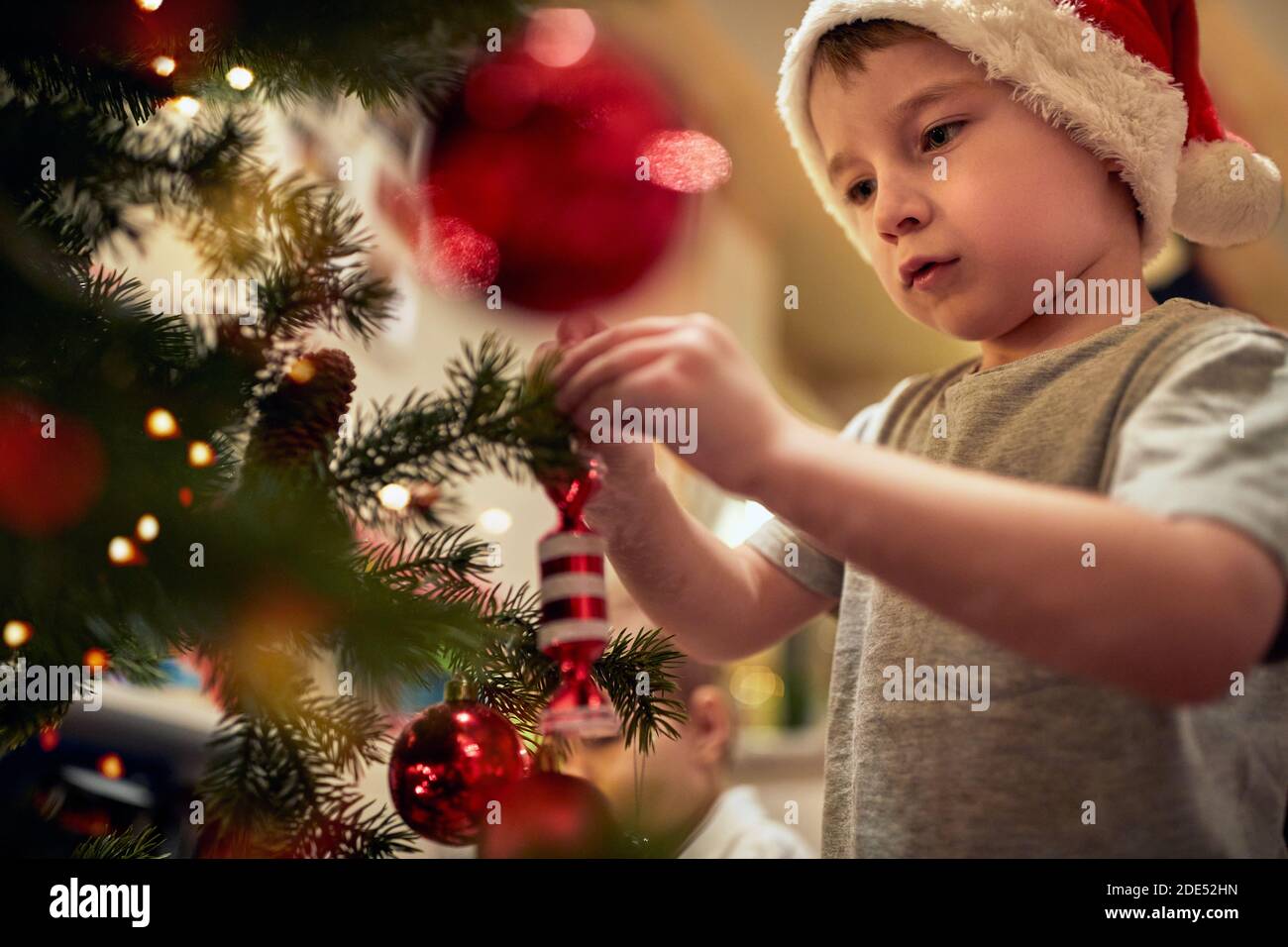 Kids participating in Christmas tree decoration in a holiday atmosphere at home. Together, New Year, family, celebration Stock Photo