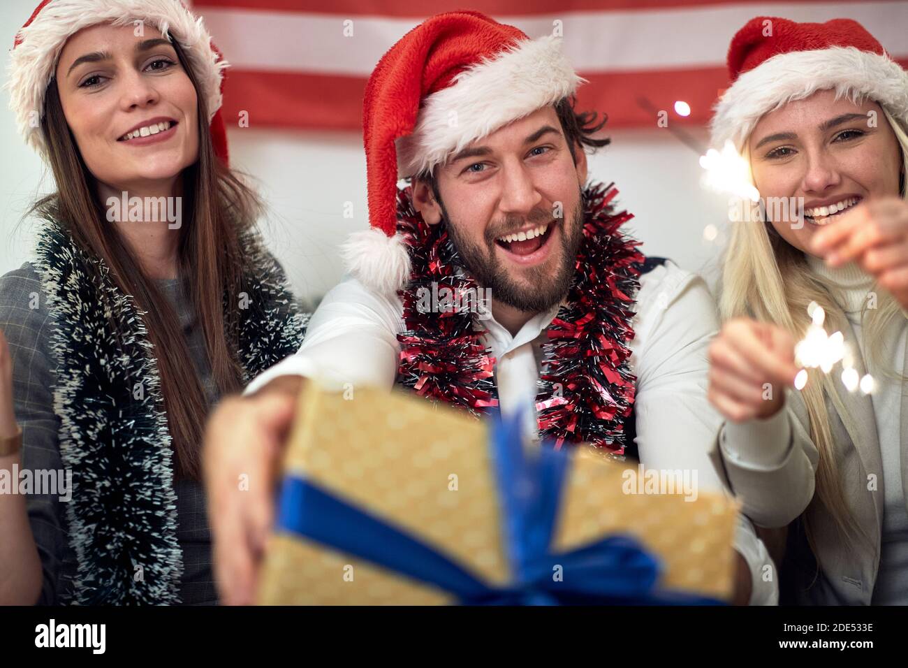 A group of cheerful friends celebrating Christmas with presents and sprinklers at a home party in a holiday atmosphere. Christmas, friendship, togethe Stock Photo