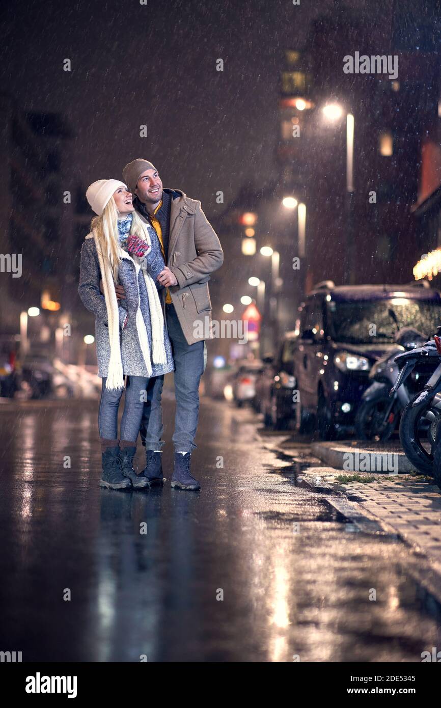 young caucasian couple looking up, smiling, watching snow falling Stock Photo