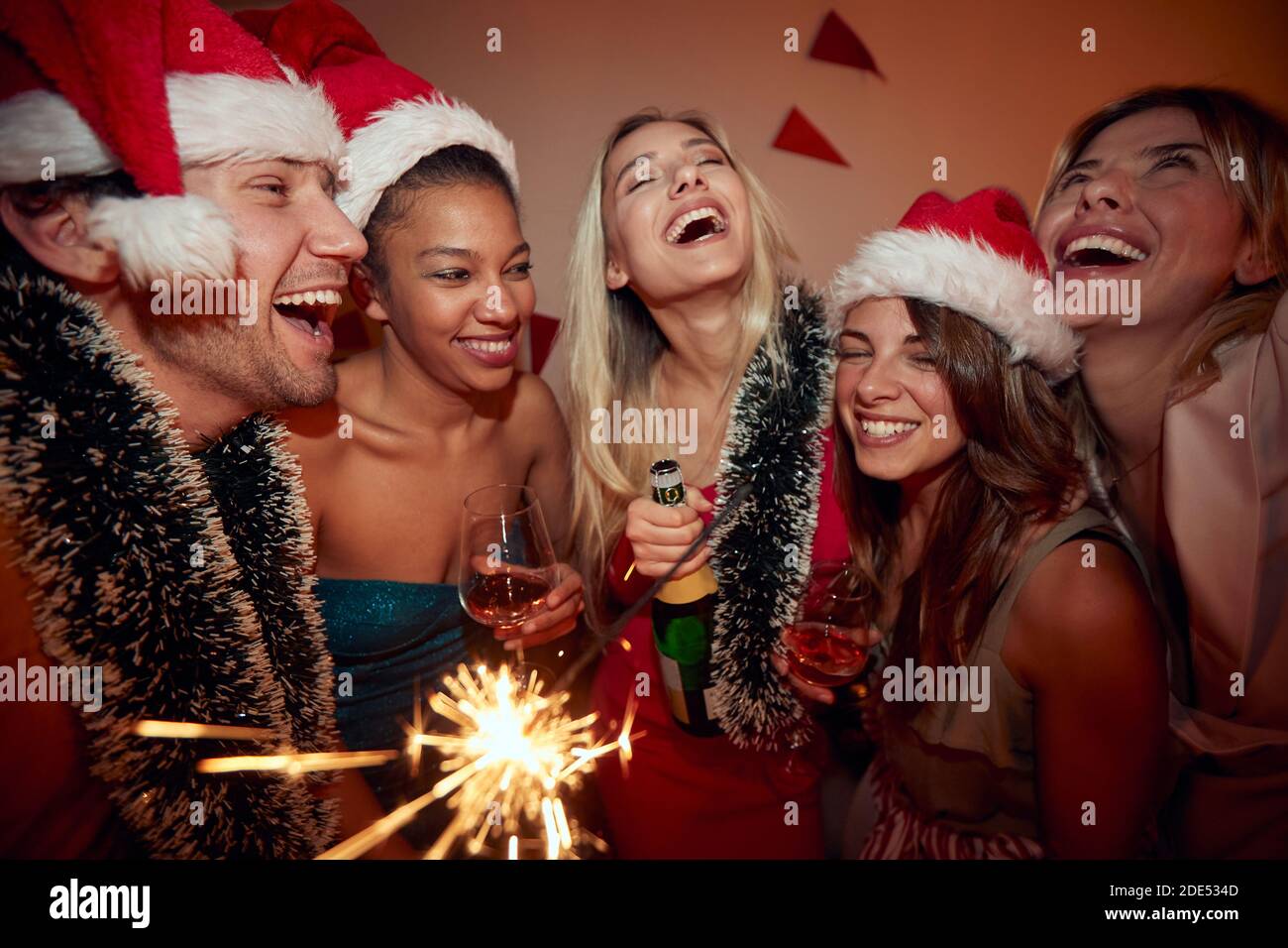 group of people at new year party, drinking alcohol, wearing santa hats Stock Photo
