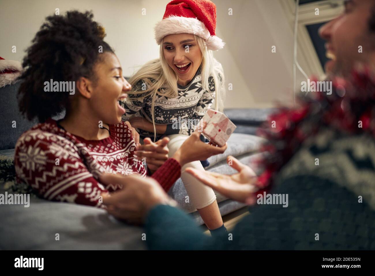 group of young multiethnic friends laughing, enjoying, exchanging gifts on christmas Stock Photo
