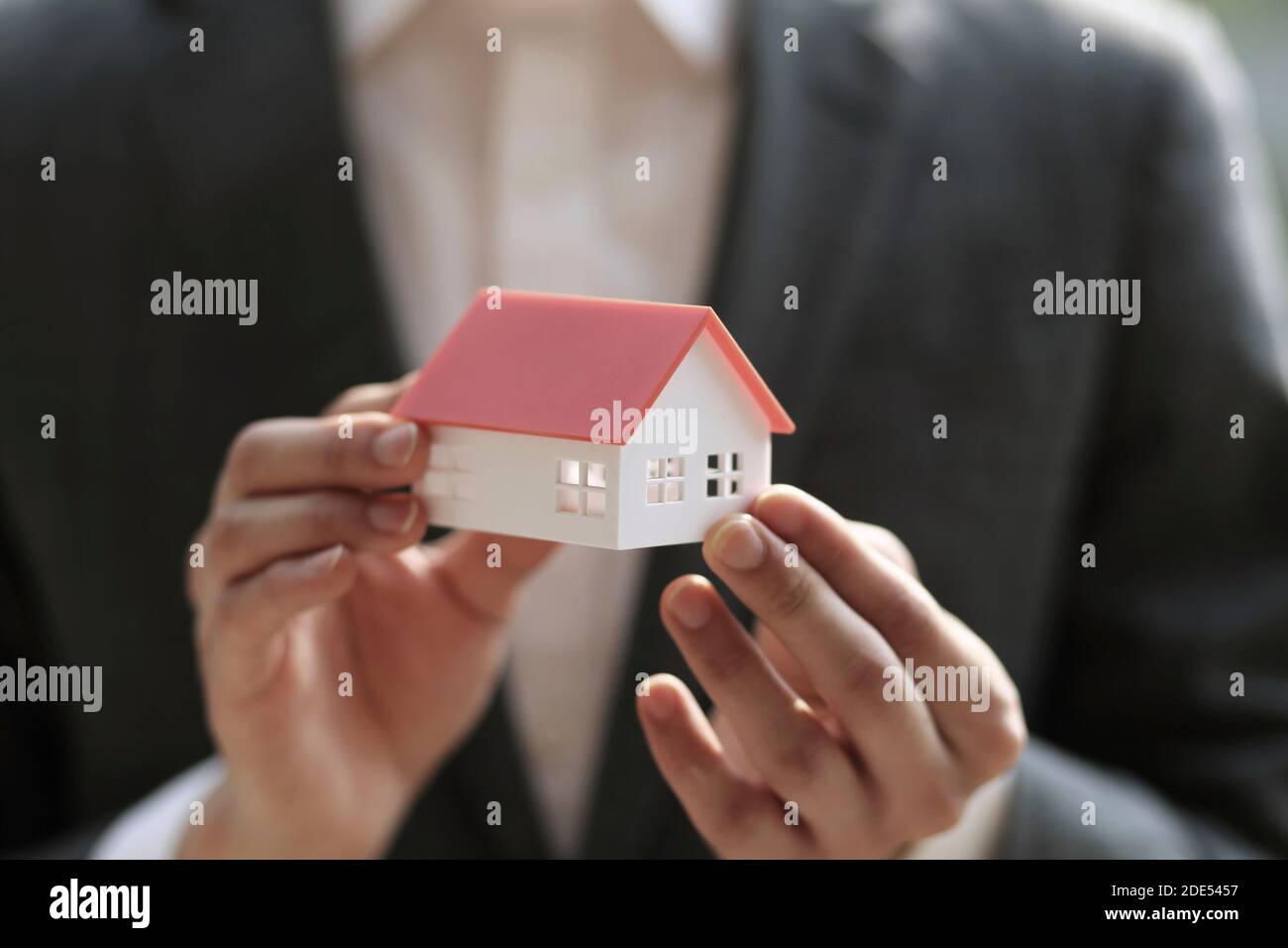 Close up of businessman holding model house. Architecture, building, construction, real estate and property concept Stock Photo