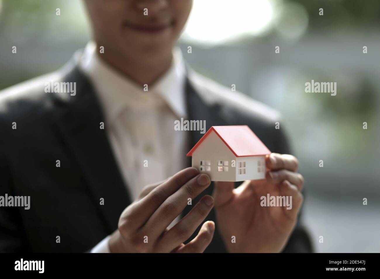 Businessman holding model house. Architecture, building, construction, real estate and property concept Stock Photo