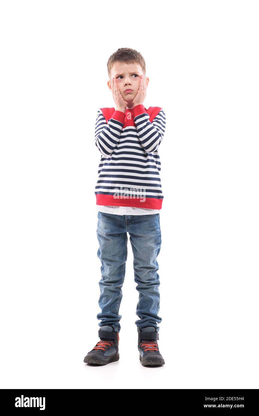 Worried confused little boy looking up wondering with head in hands. Full body portrait isolated on white background. Stock Photo