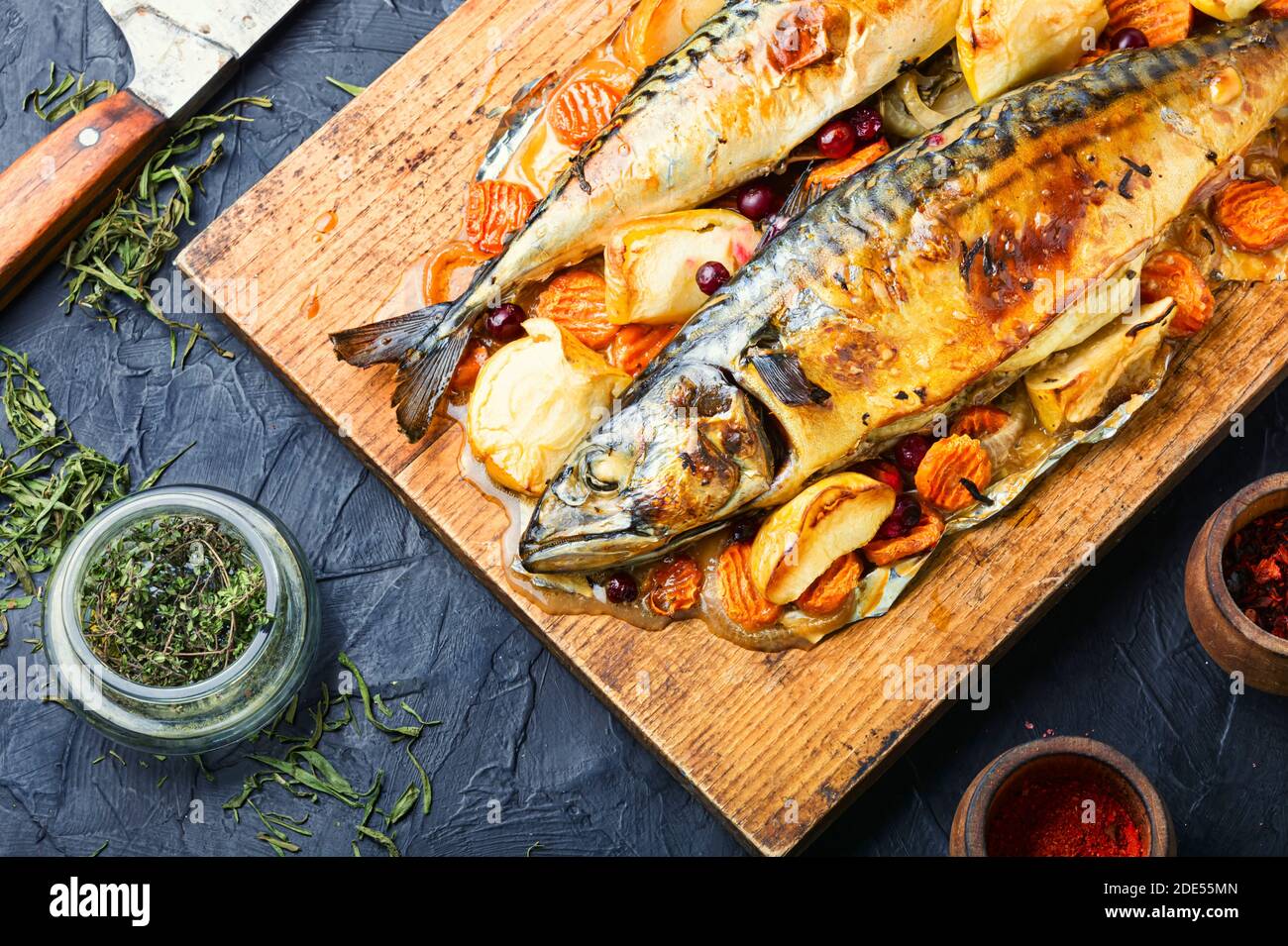 Delicious mackerel fish roasted with apples,served on kitchen board. Stock Photo