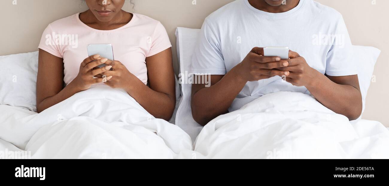 Unrecognizable black couple using smartphones in bed Stock Photo