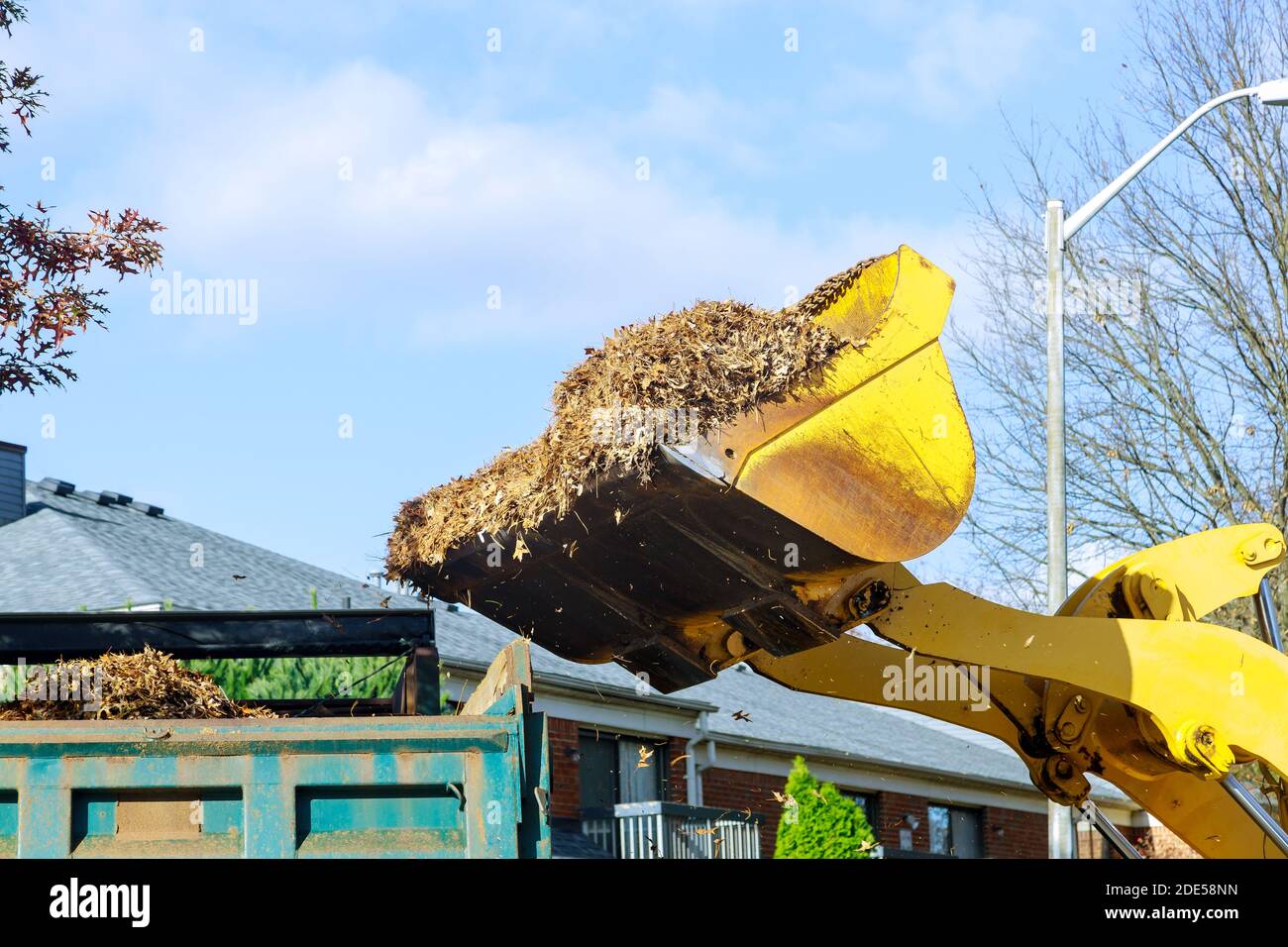 Cleans the sidewalk of the city from fallen leaves with an excavator regular seasonal work on improving the public places Stock Photo