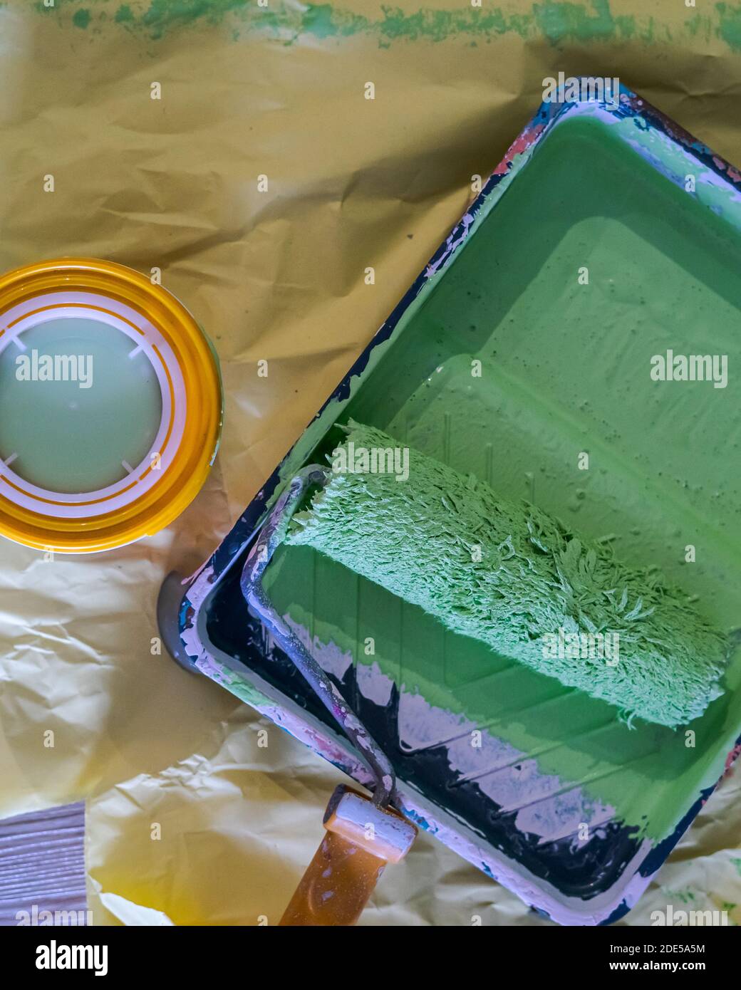 Paint roller in paint tray with green color in the tray on yellow paper Stock Photo Alamy