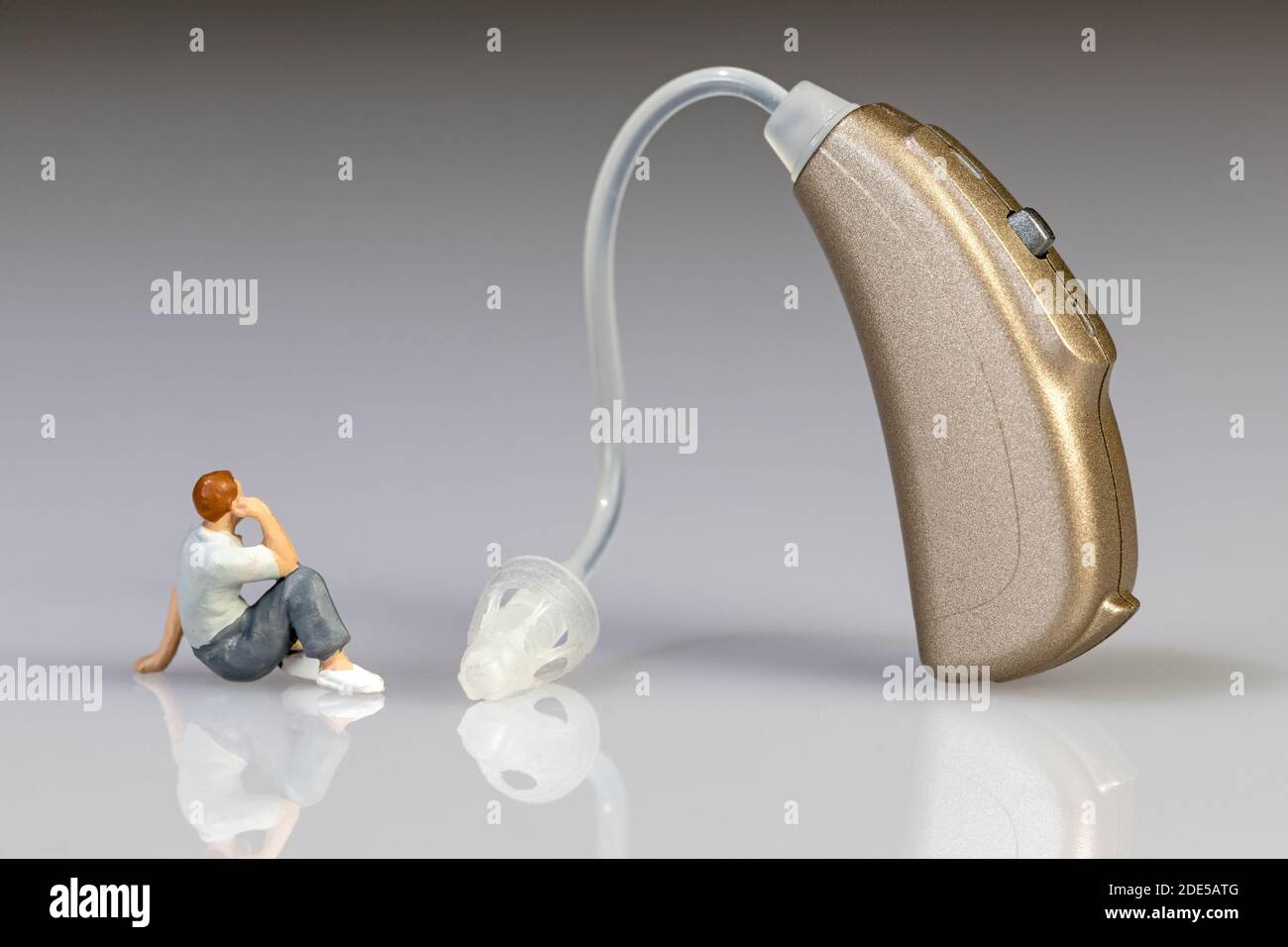 cut out of a hearing aid with miniature figure of a user Stock Photo