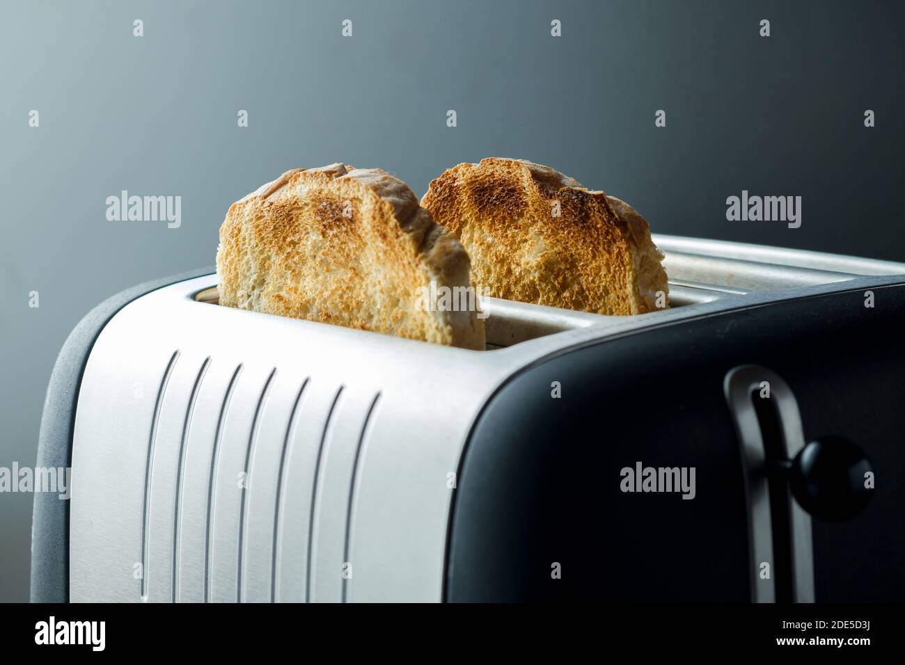 Freshly made toasted bread popped up in a modern toaster. The bread is browned and toasted ready to be eaten for breakfast Stock Photo