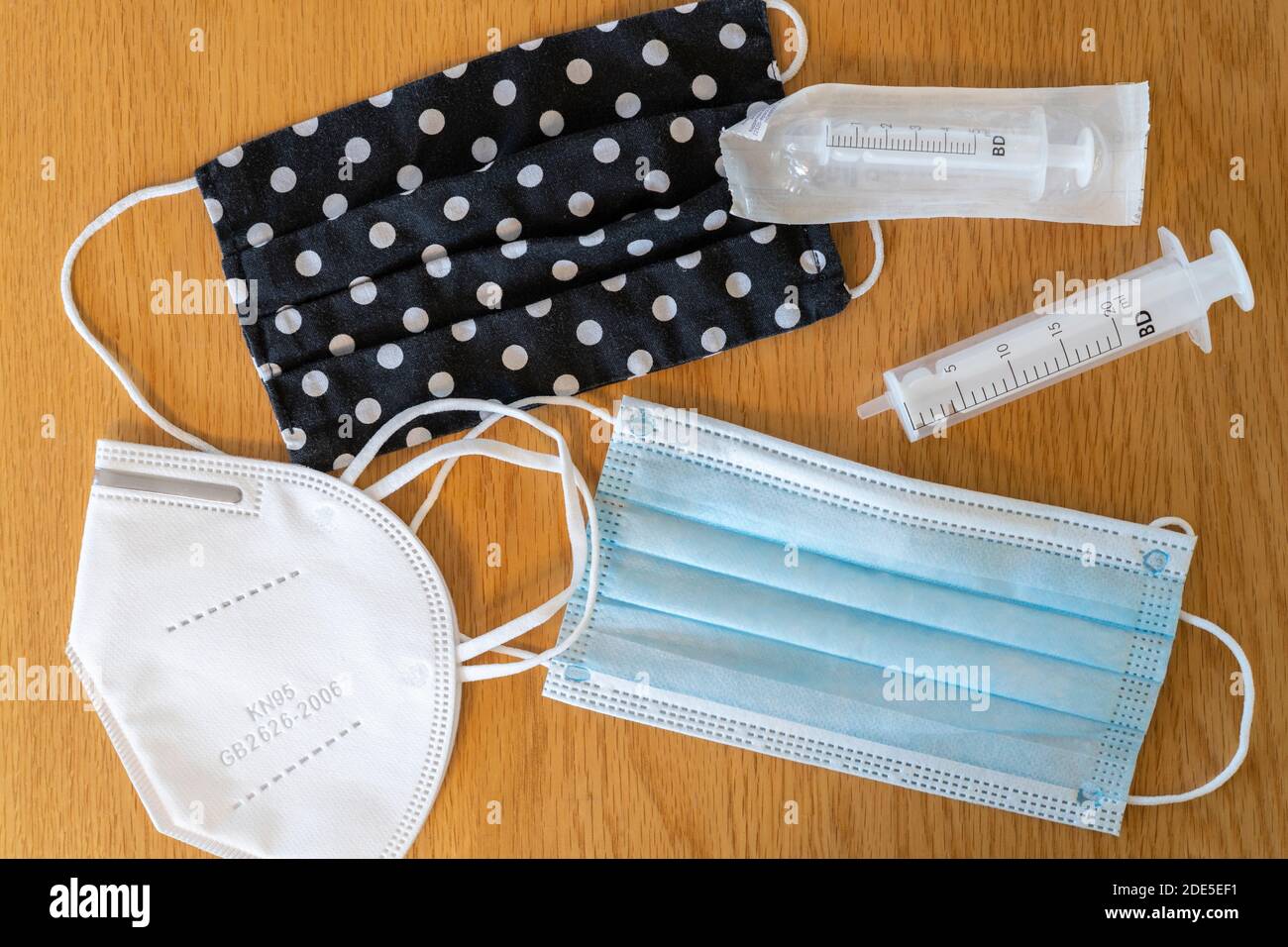 A selection of disposable face masks and a home made spotty mask, with a sealed and opened syringe during the Coronavirus Covid-19 pandemic, UK Stock Photo