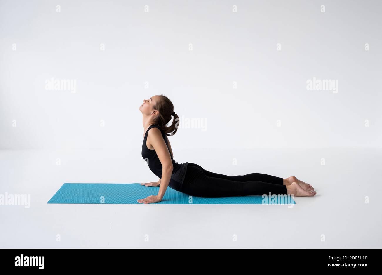Young woman practicing yoga, lying and stretching in Cobra pose, doing ...