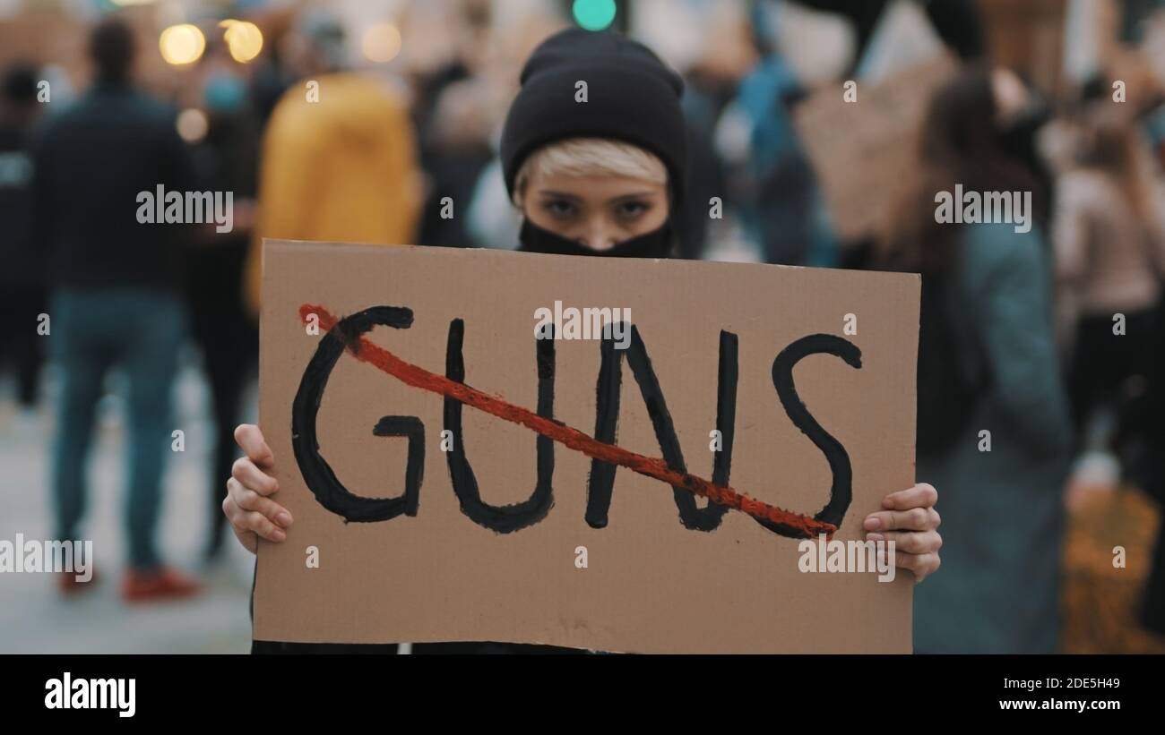 No guns. Young woman with face mask holding banner against gun violence ...