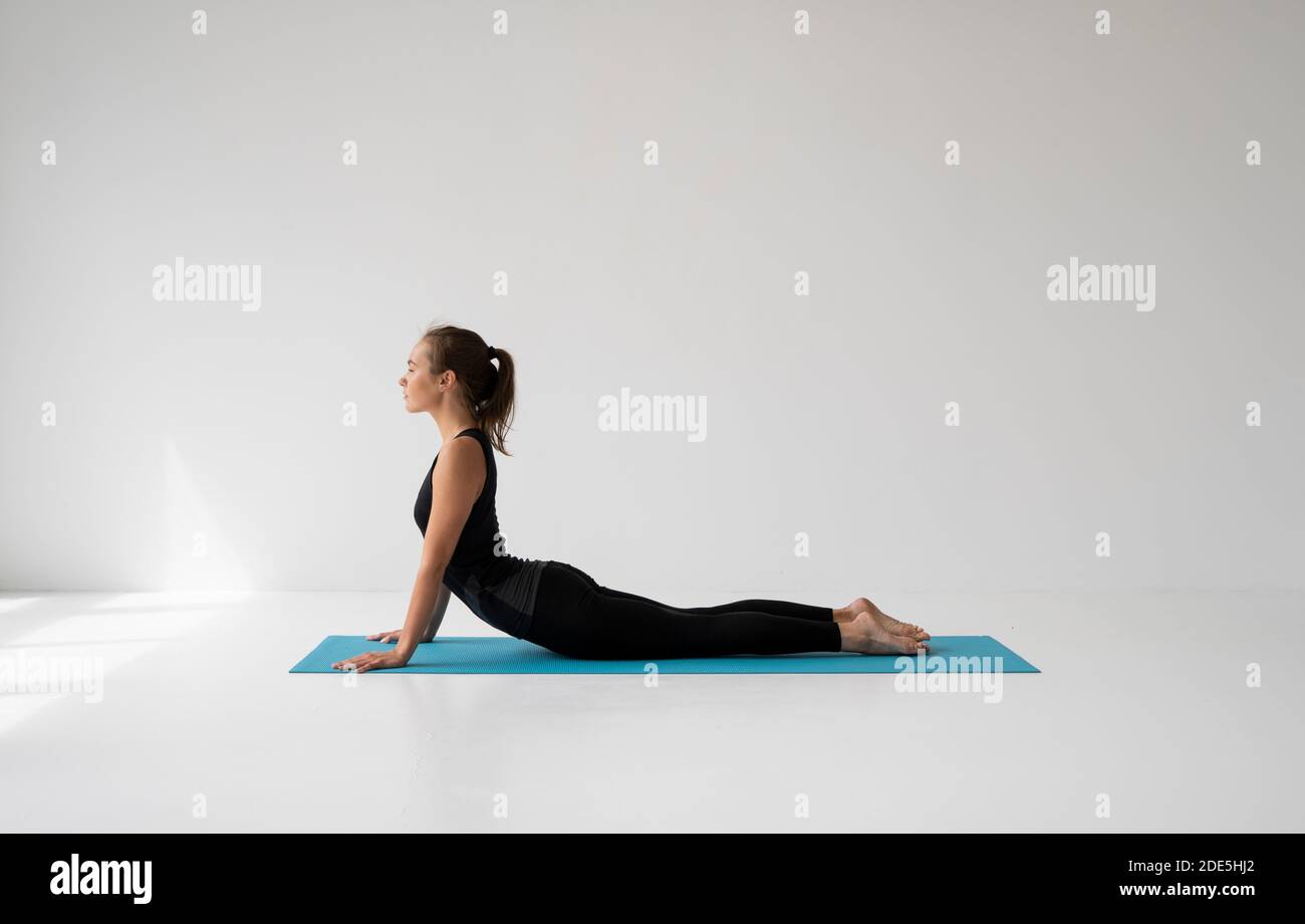 Young woman practicing yoga, lying and stretching in Cobra pose, doing ...
