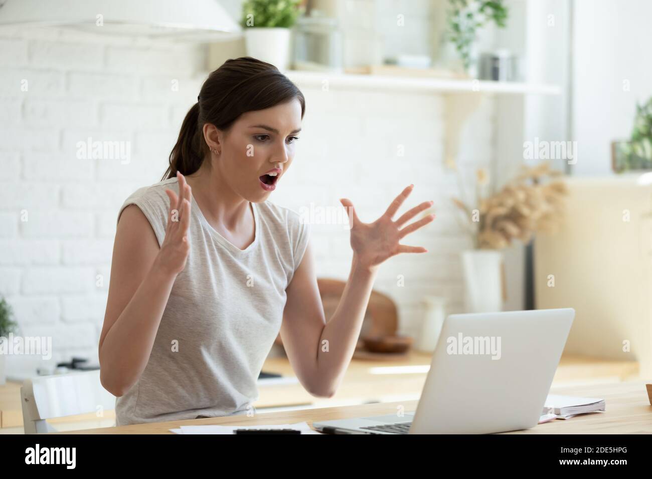 Angry shocked young woman looking at laptop screen, reading news Stock Photo