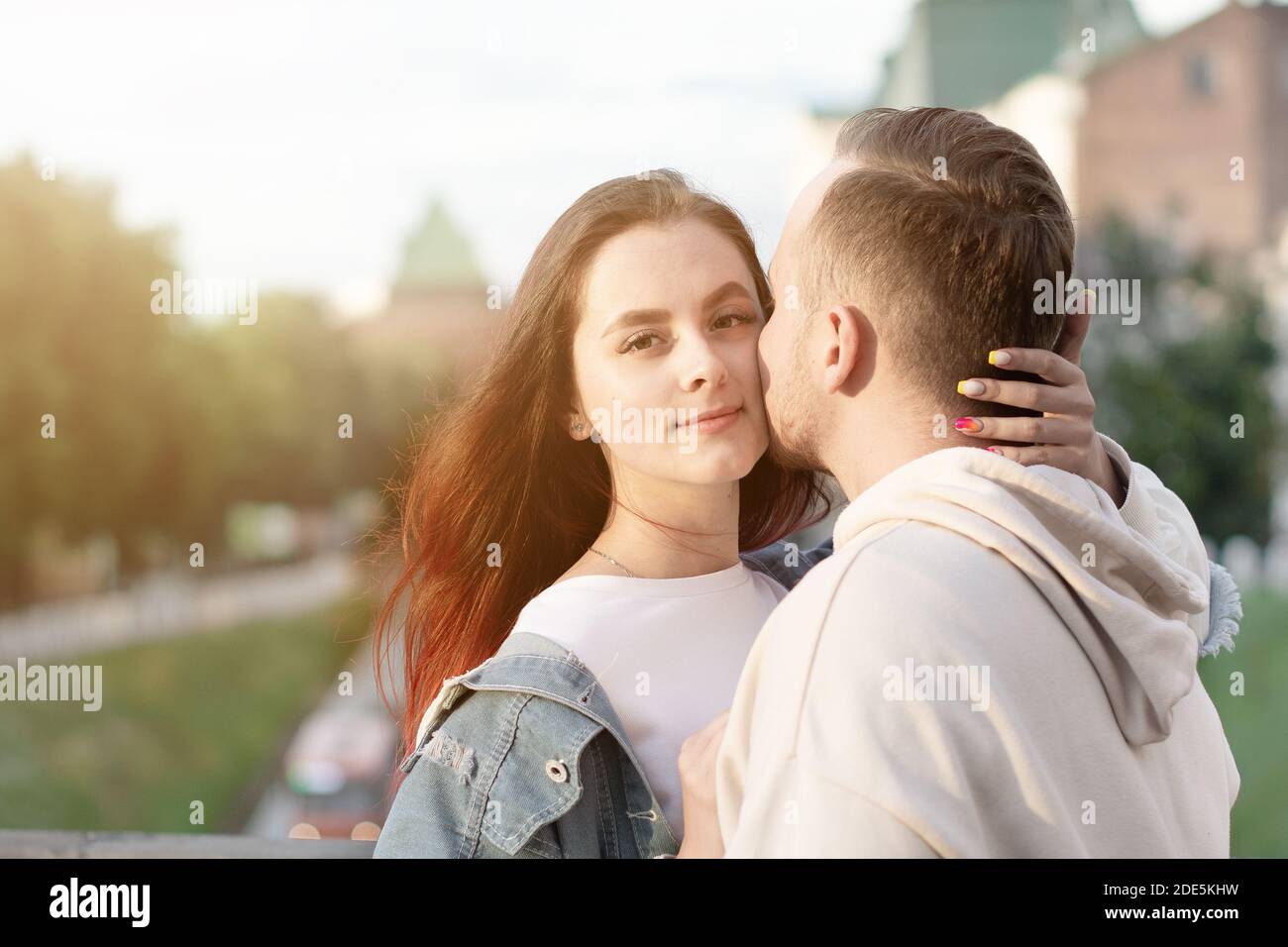 Happy young couple caucasian woman and man is sharing smile and walking in street summer. Concept couple in love. Female is hugging her husband Stock Photo